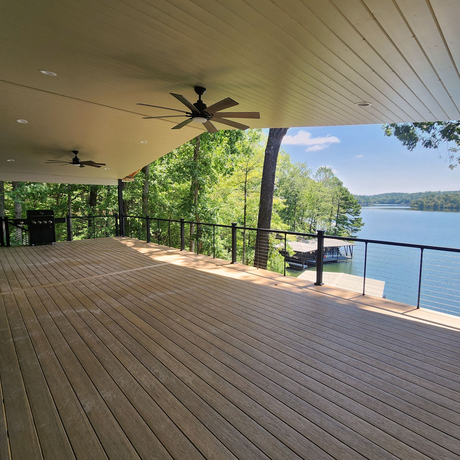 A large deck with a ceiling fan overlooking a lake