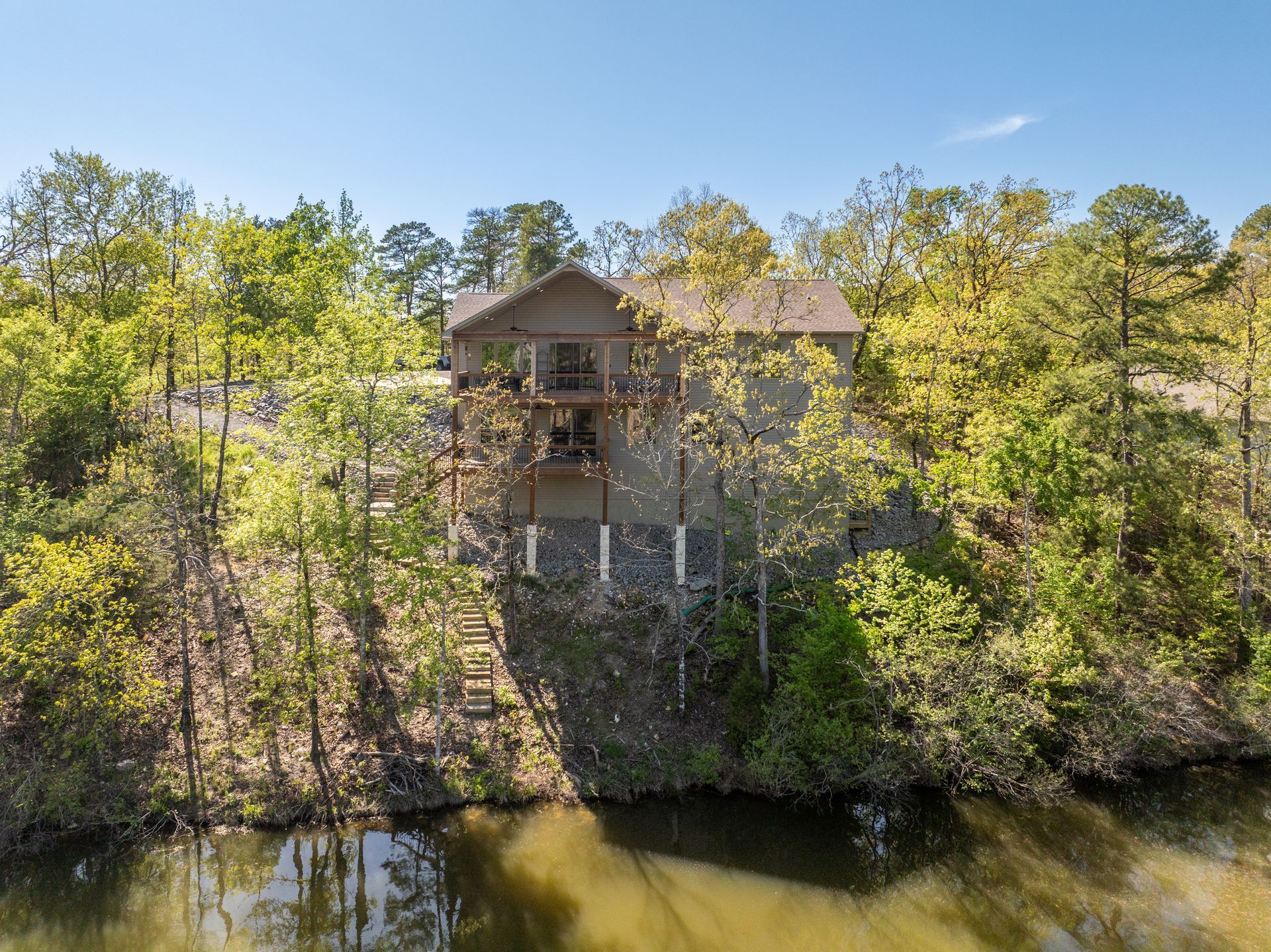An aerial view of a house next to a lake surrounded by trees.