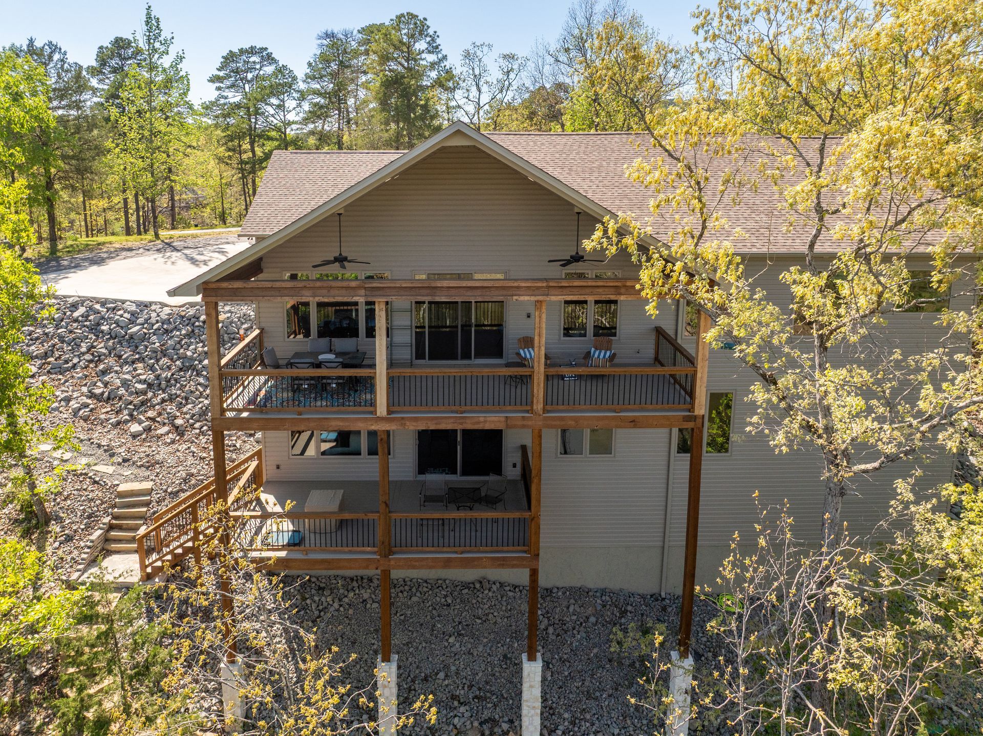 An aerial view of a log cabin with a large deck surrounded by trees.
