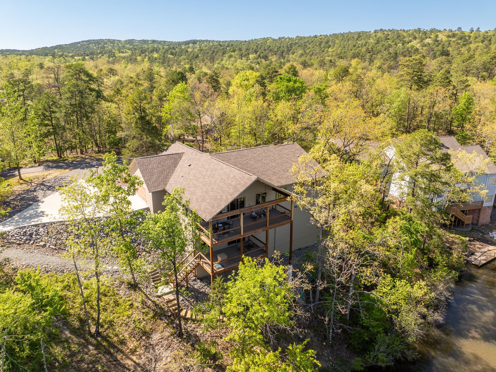 An aerial view of a house in the middle of a forest surrounded by trees.