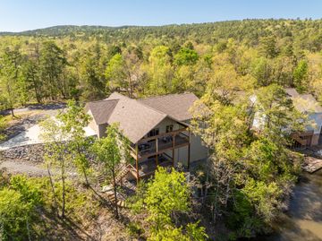 An aerial view of a house in the middle of a forest surrounded by trees.
