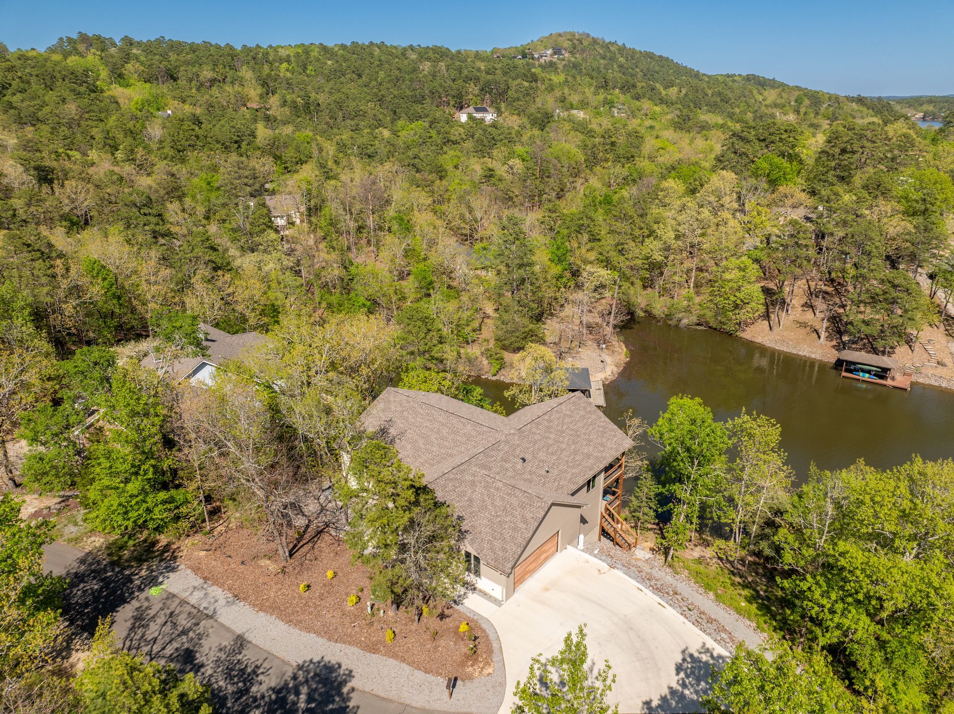 An aerial view of a house surrounded by trees and a lake.