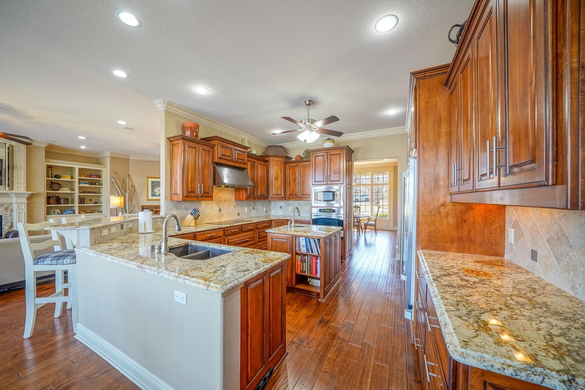 A large kitchen with granite counter tops and wooden cabinets.
