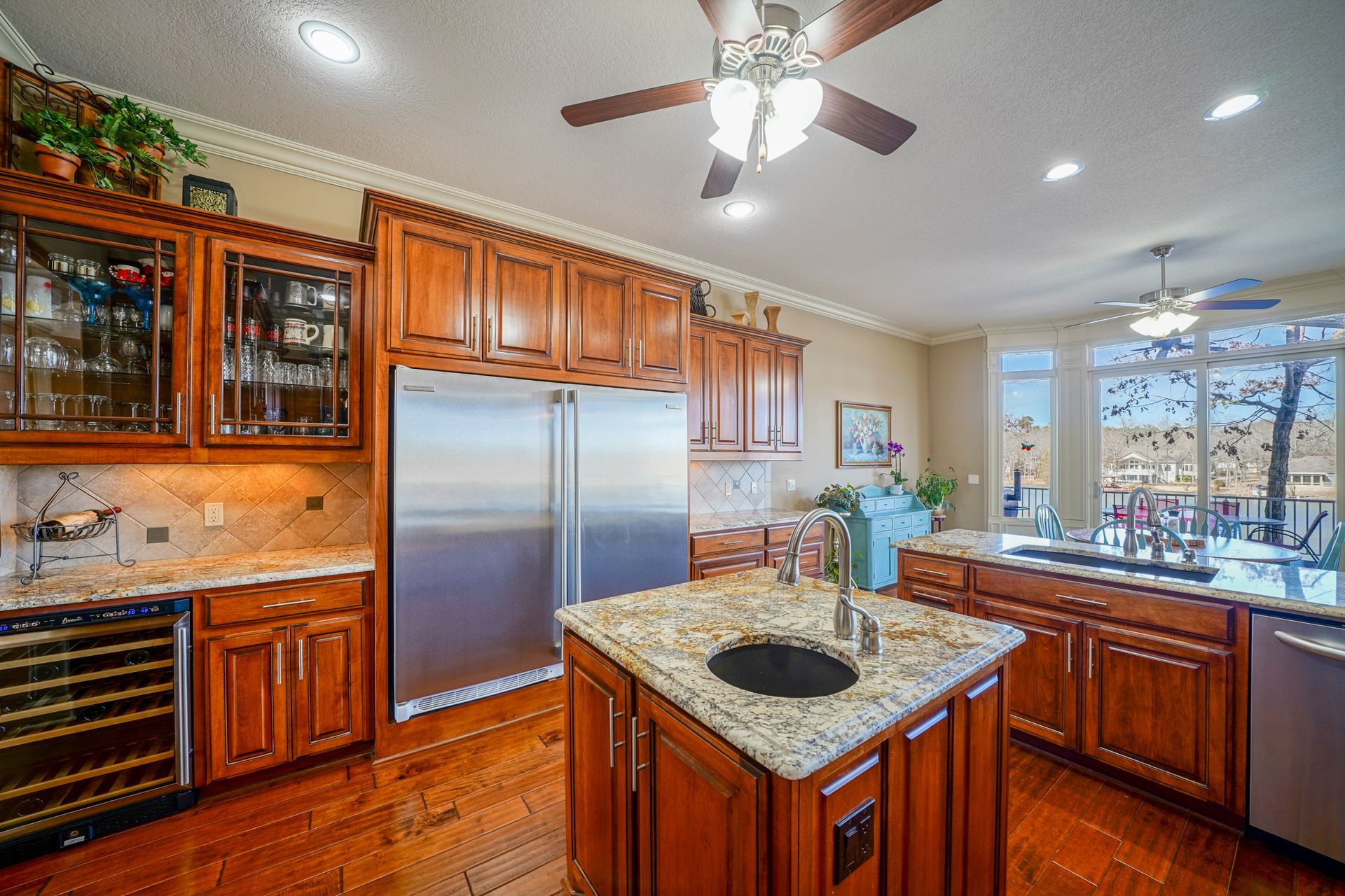 A kitchen with wooden cabinets , granite counter tops , stainless steel appliances and a ceiling fan.