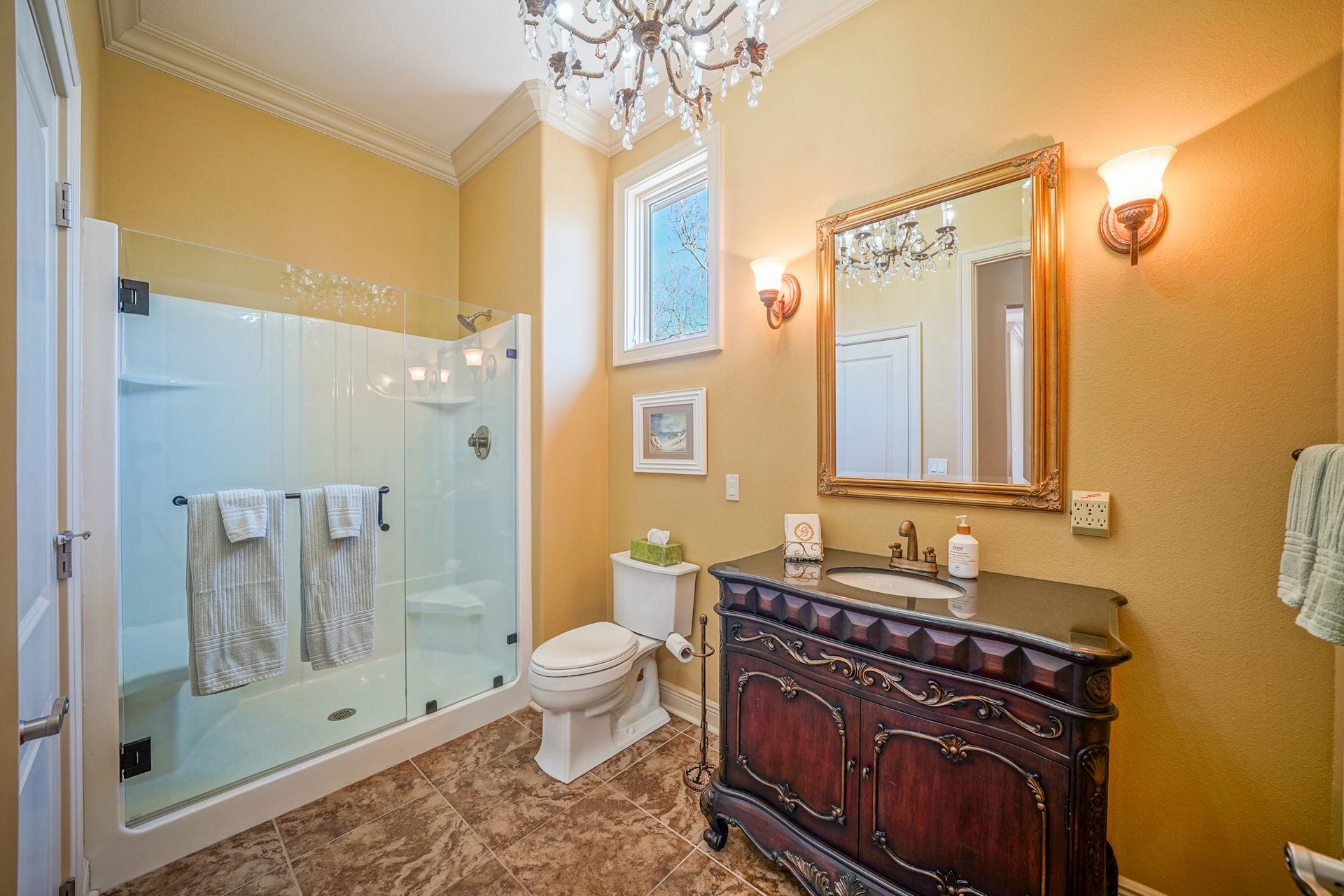 A bathroom with a toilet , sink , mirror and walk in shower.