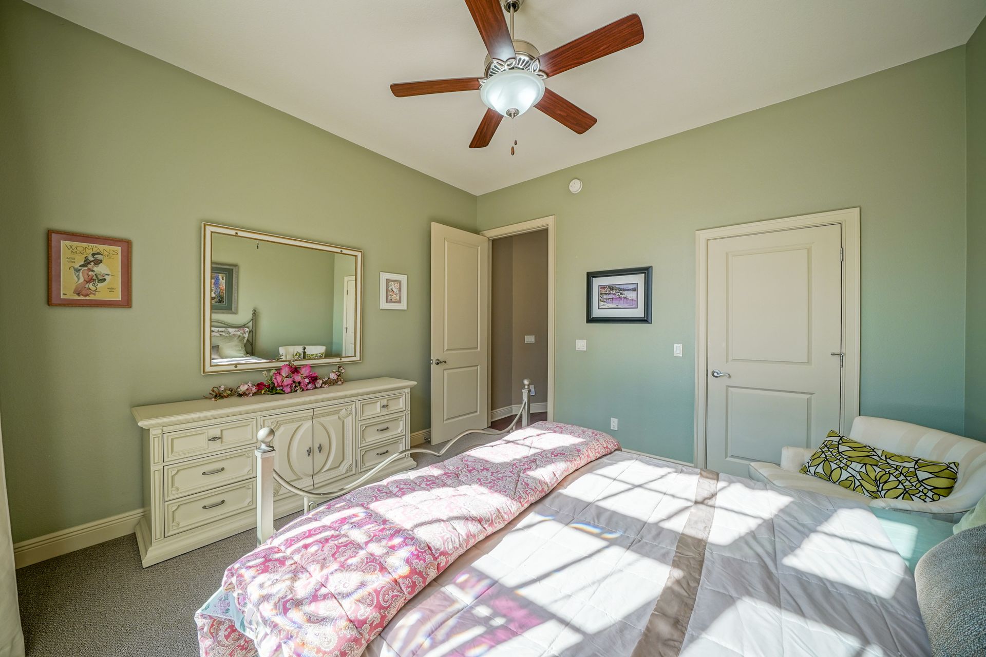 A bedroom with a bed , dresser , mirror and ceiling fan.
