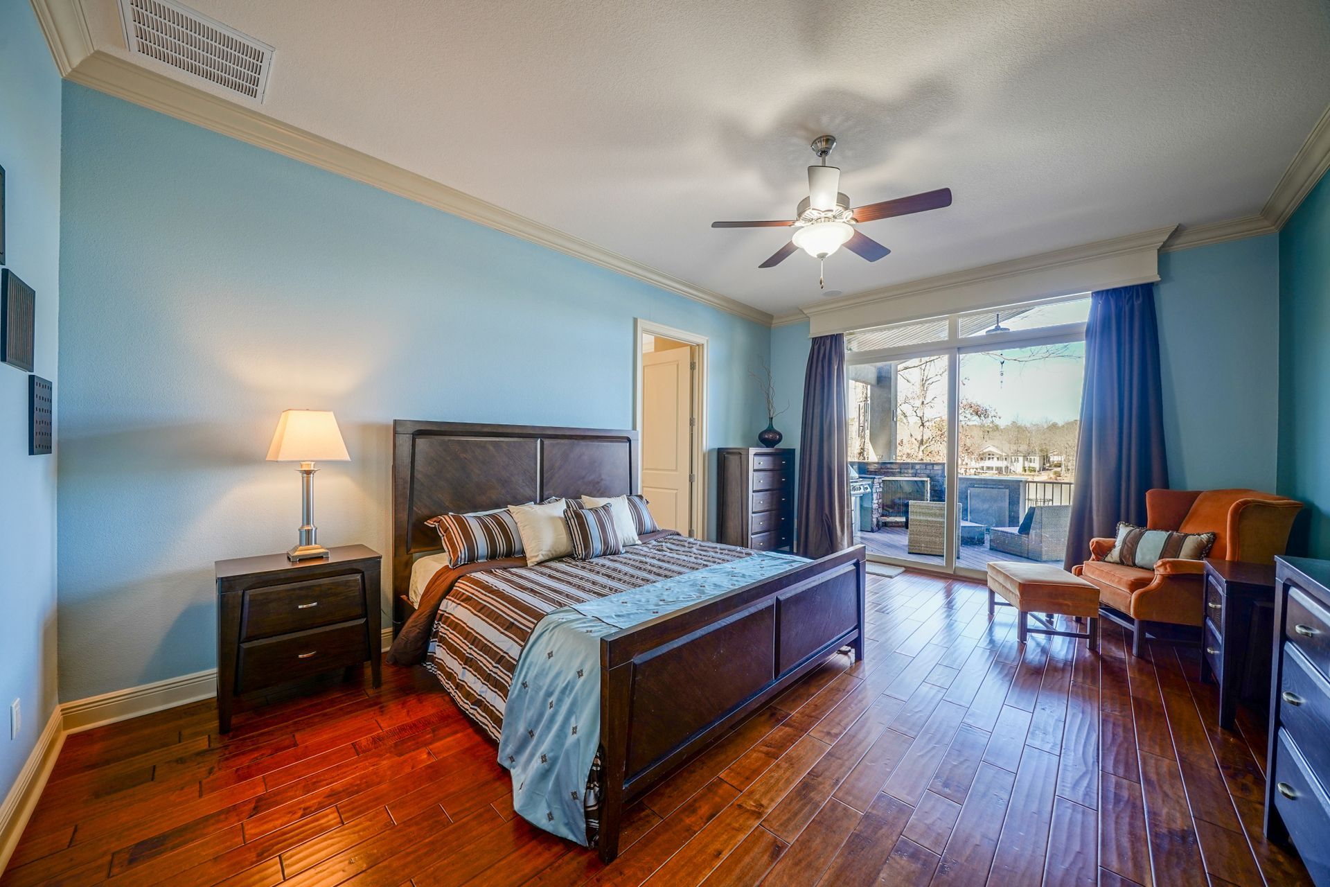 A bedroom with a king size bed , nightstands , a ceiling fan , and hardwood floors.