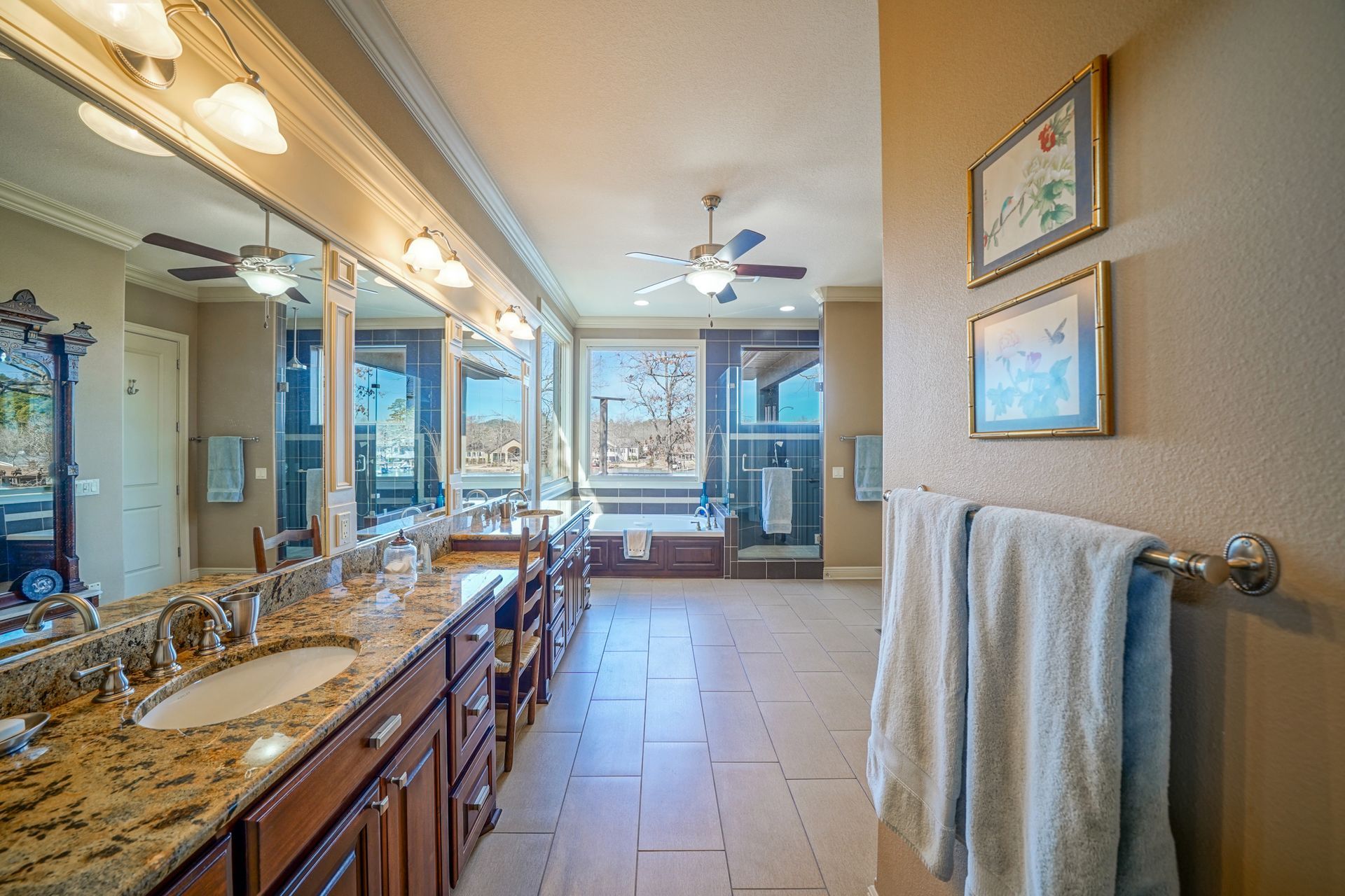 A bathroom with two sinks , two mirrors , a tub and a ceiling fan.