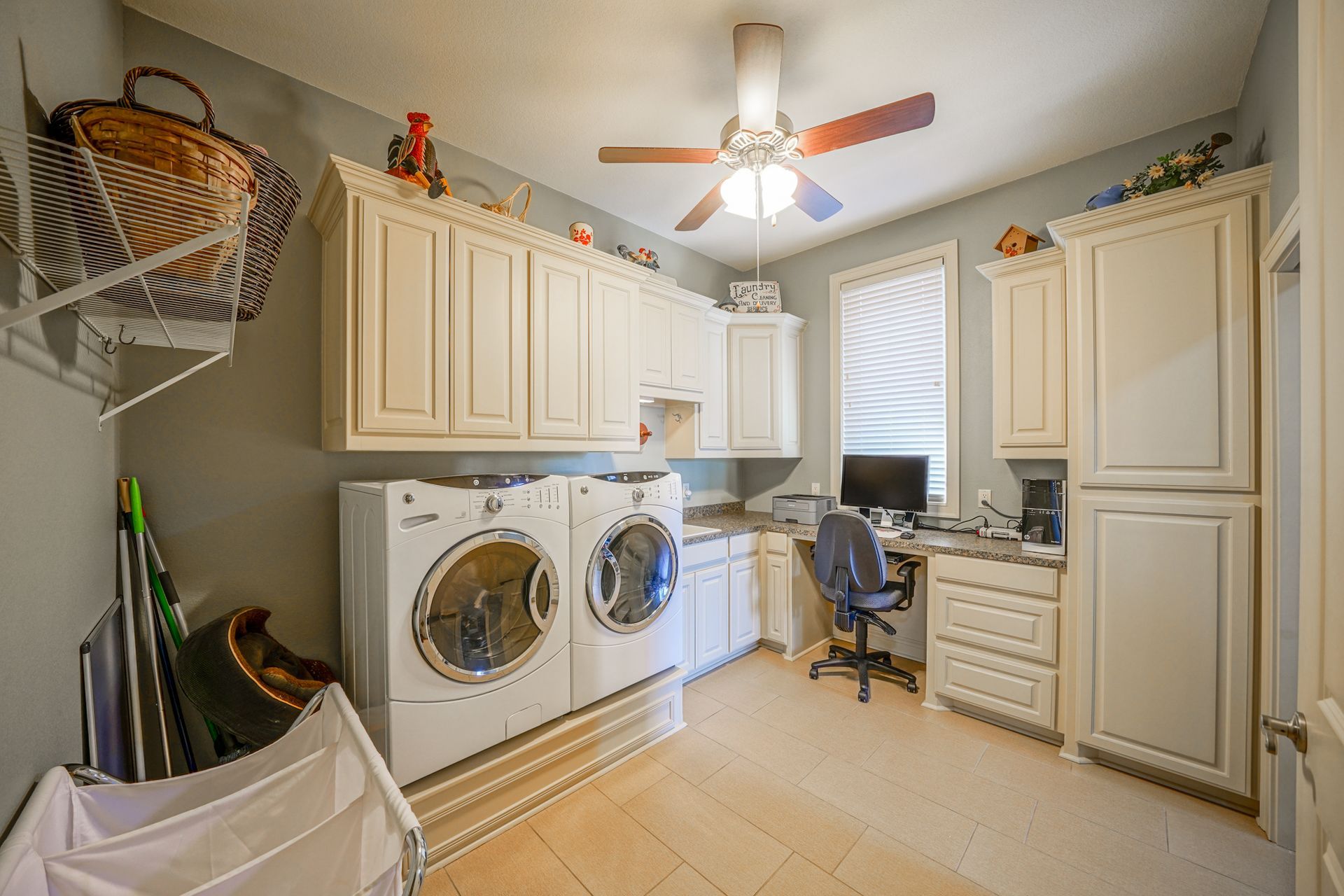 A laundry room with a washer and dryer , a desk , and a ceiling fan.