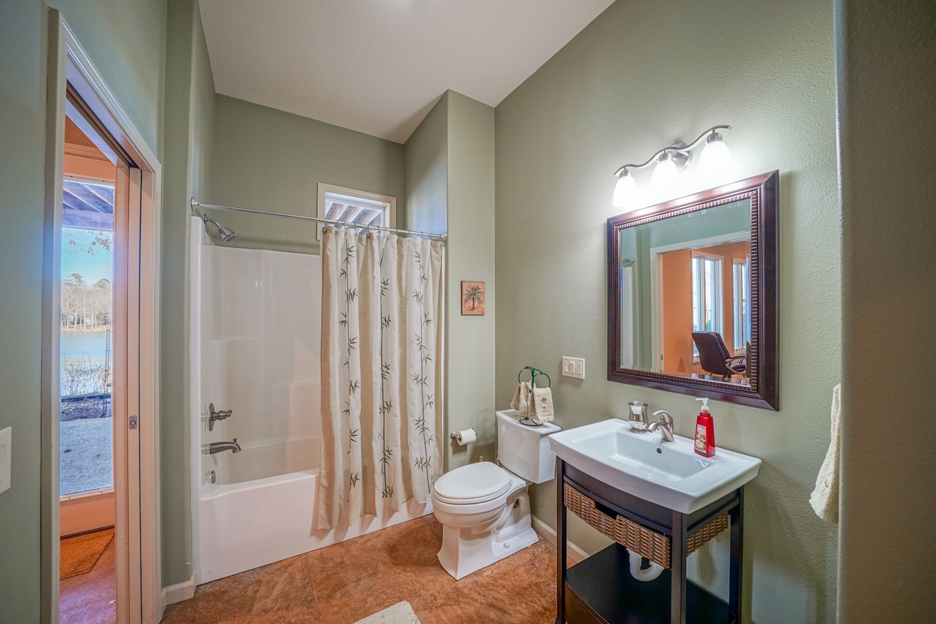 Bathroom with shower, toilet, sink, and mirror; walls are green.