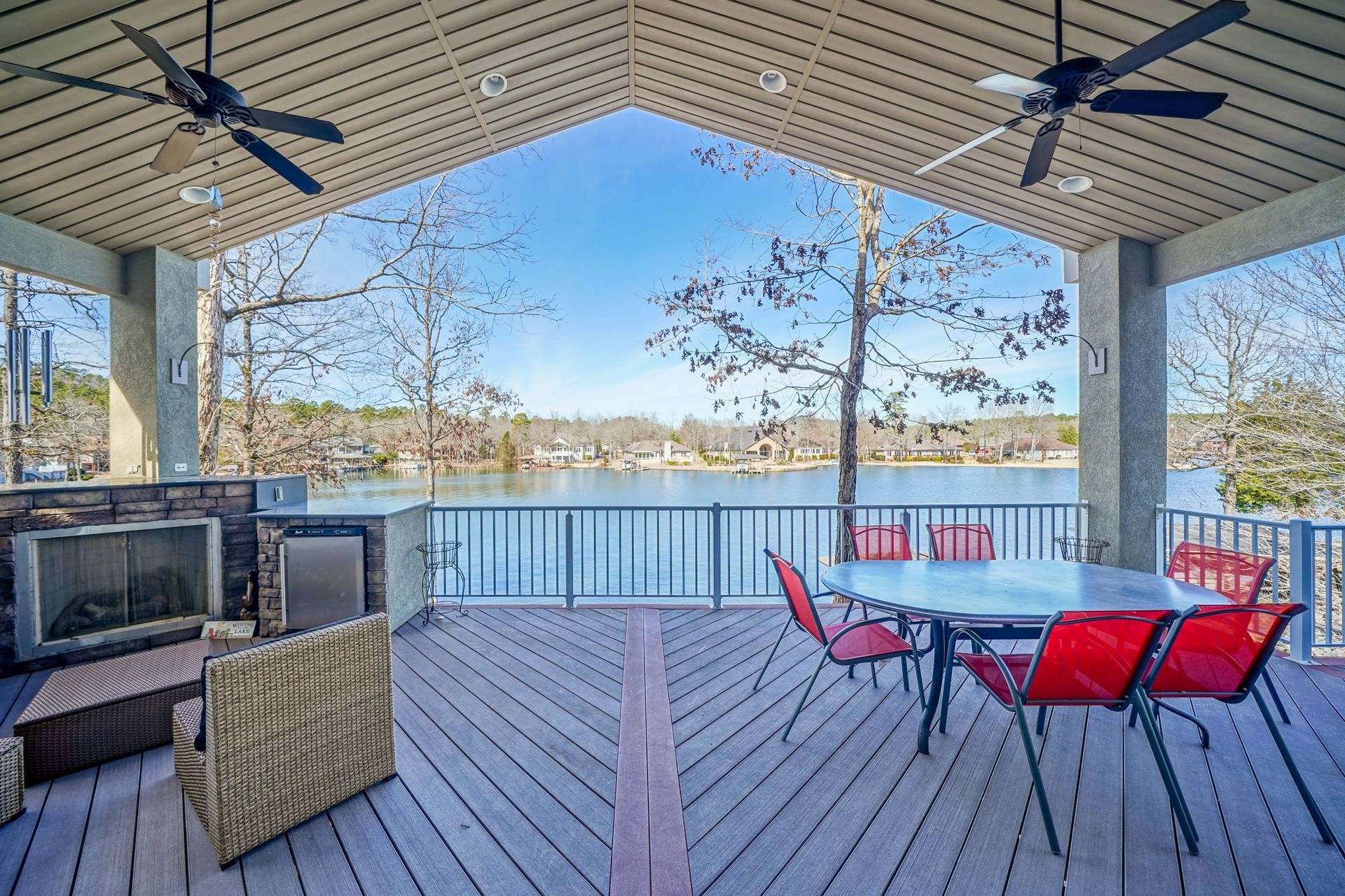 A large deck with a table and chairs overlooking a lake.