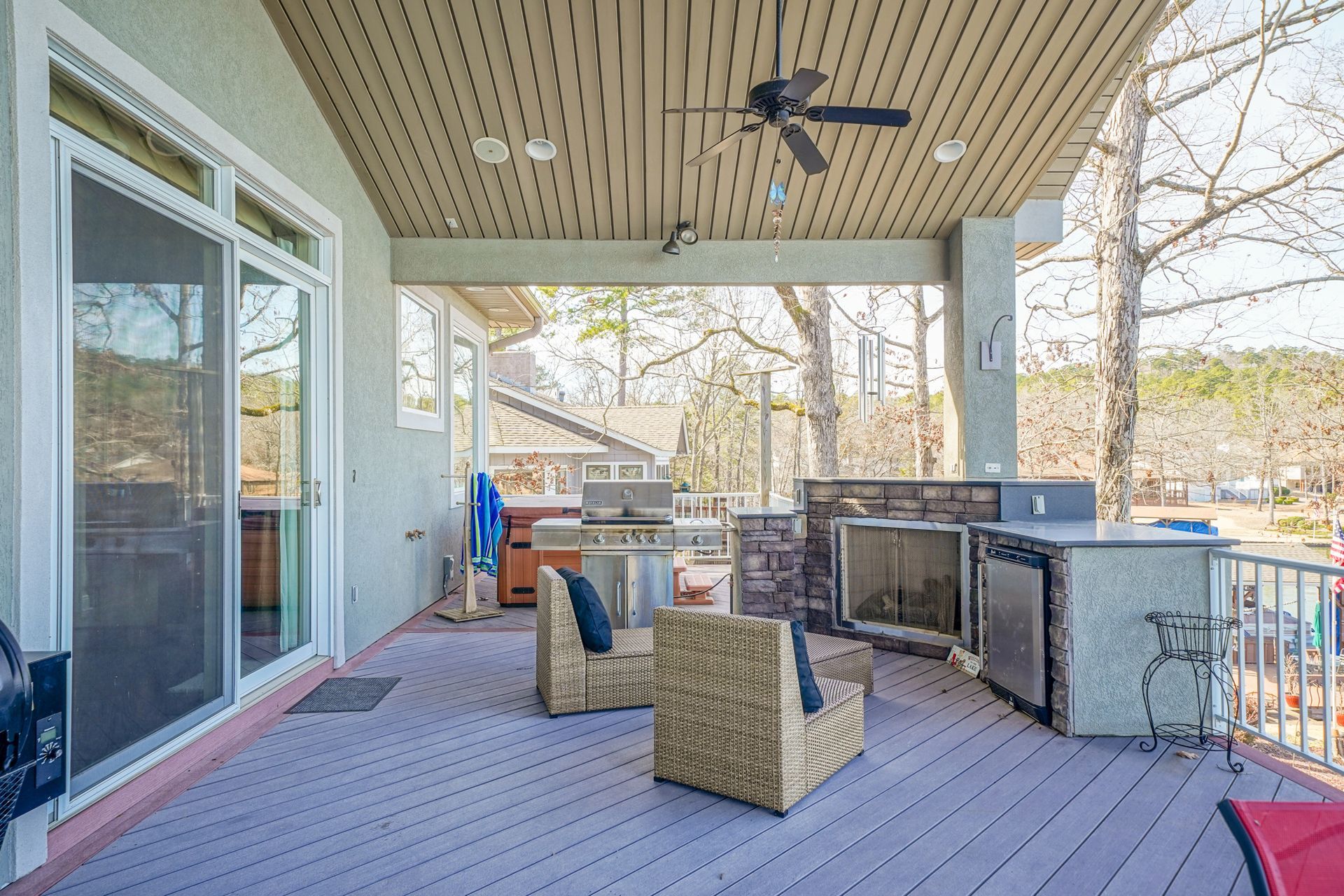 A large deck with a grill , chairs , and a ceiling fan.