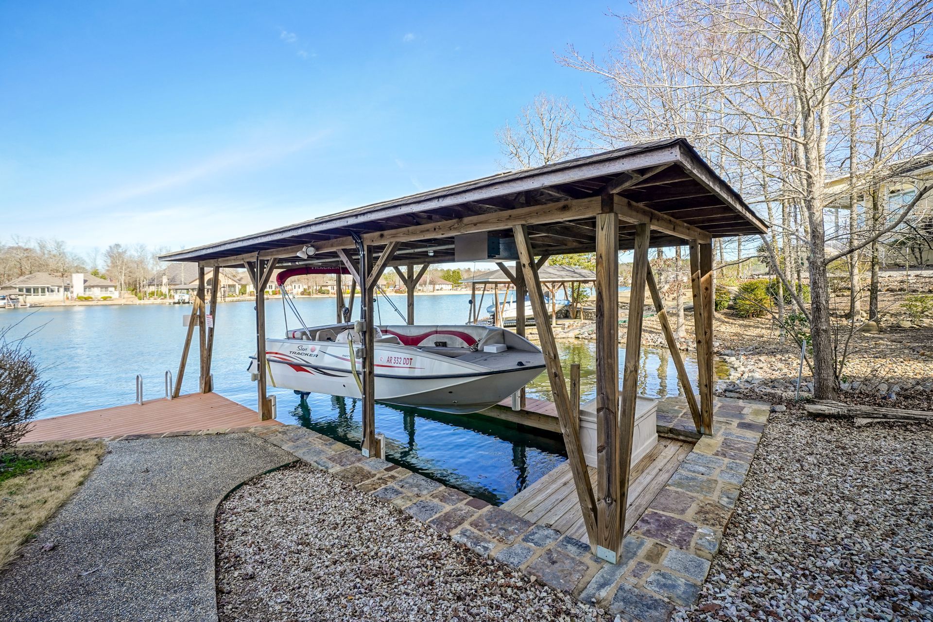 A boat is docked under a covered dock on a lake.