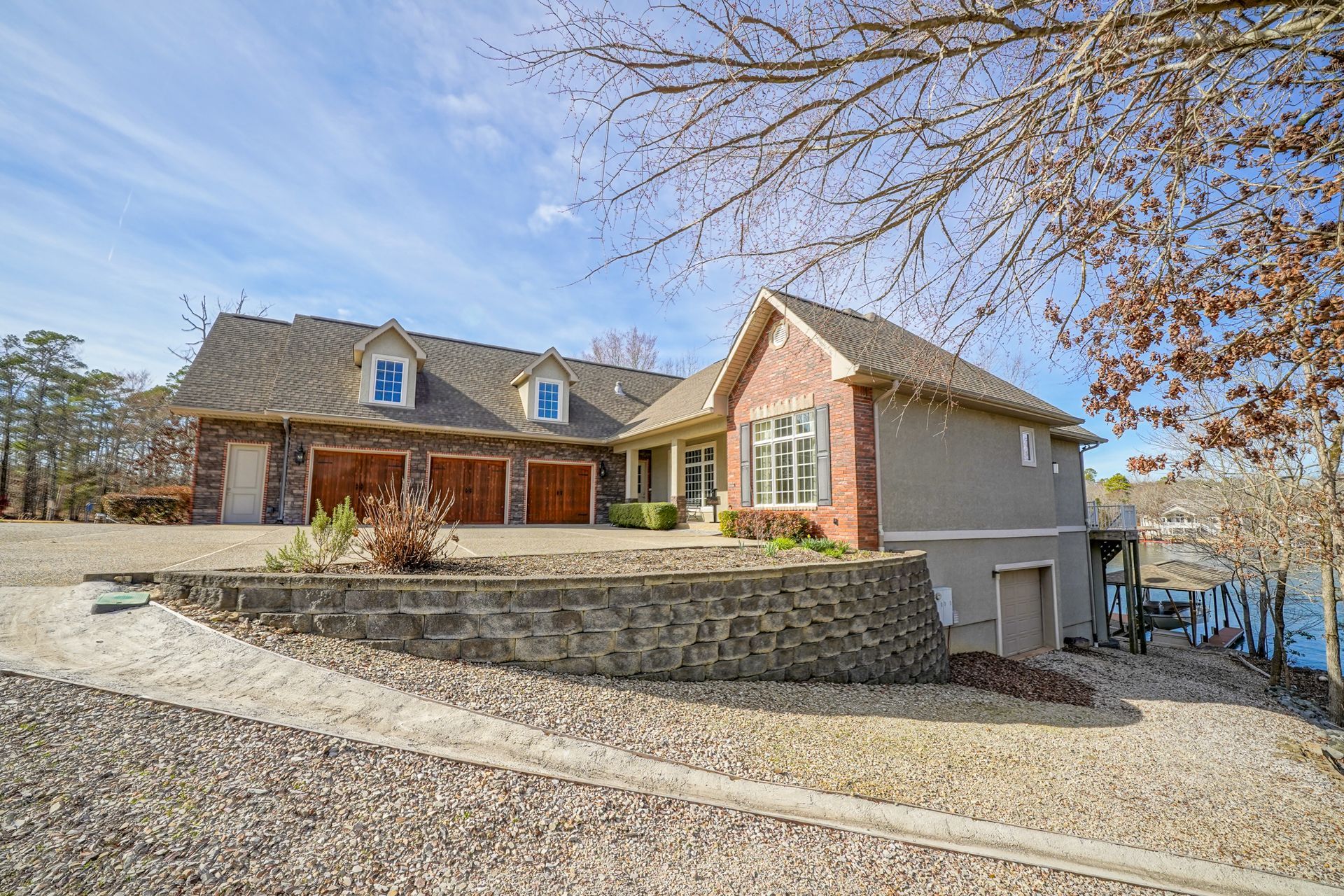 A large house with a lot of garages is sitting next to a body of water.
