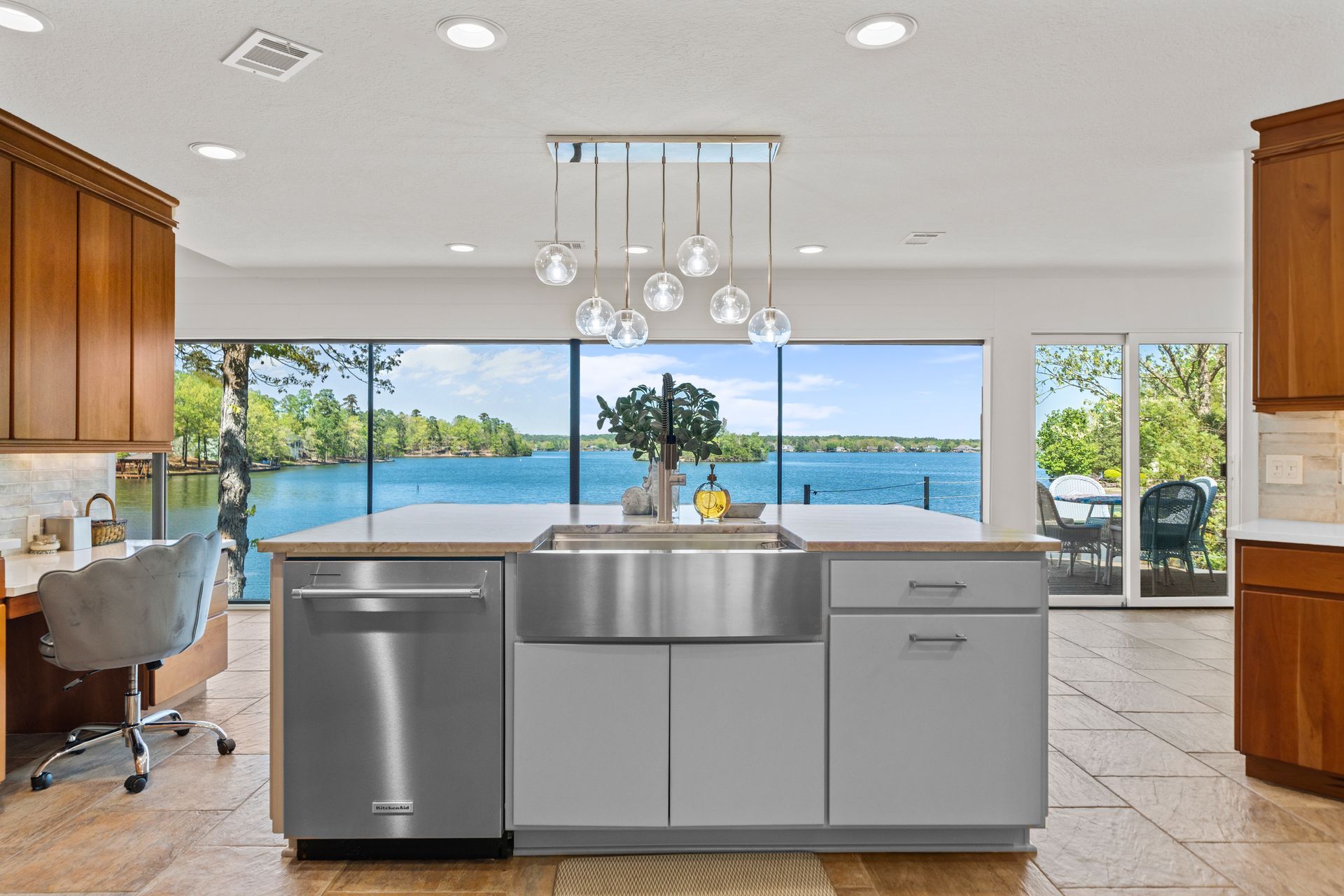 A kitchen with stainless steel appliances and a large island with a view of a lake.