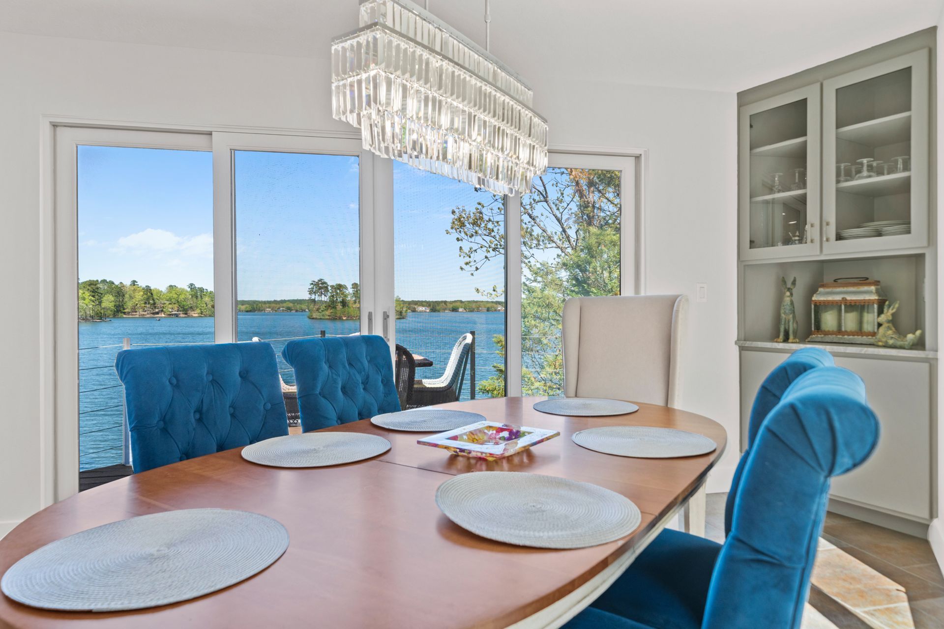 A dining room with a table and chairs and a view of a lake.