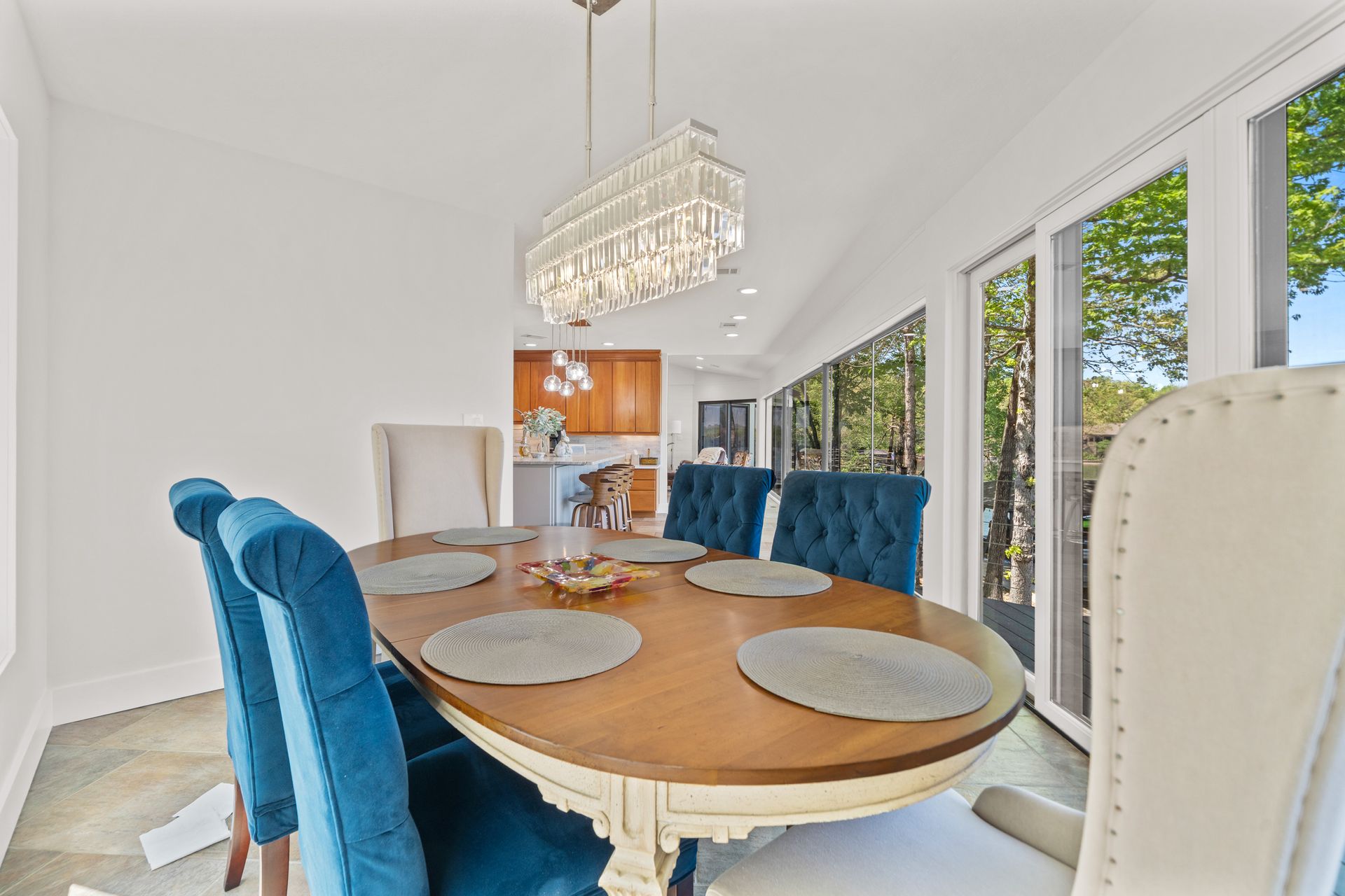 A dining room table with blue chairs and a chandelier.