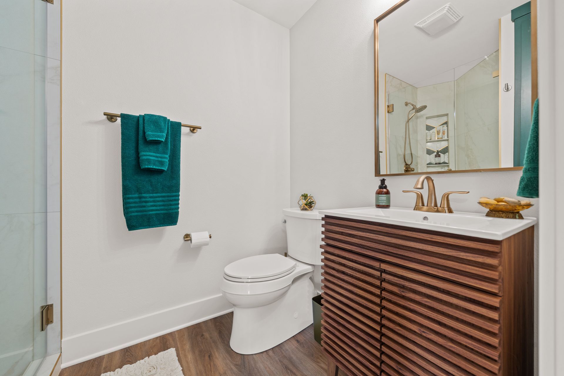 A bathroom with a toilet , sink , mirror and shower.