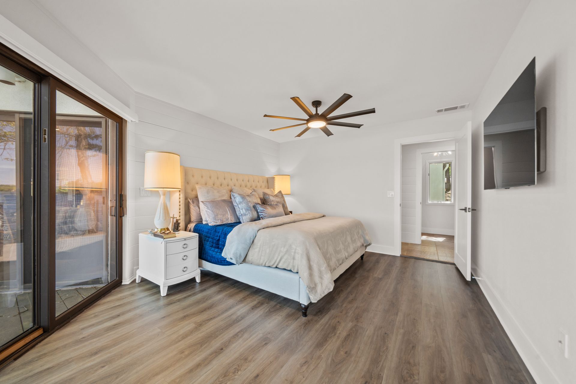 A bedroom with a large bed and a flat screen tv on the wall.