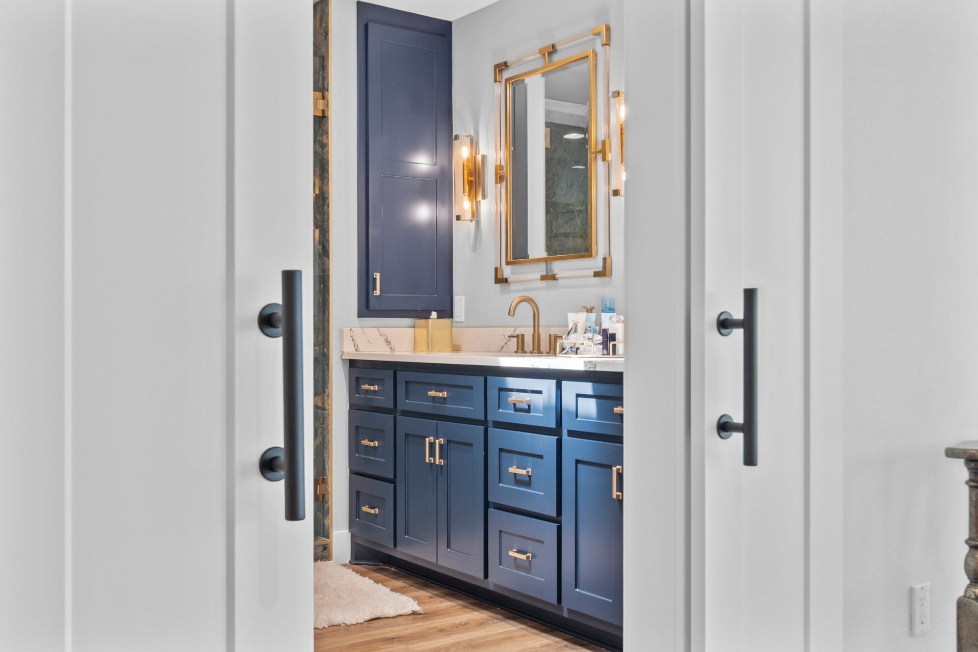 A bathroom with blue cabinets , a sink , and a mirror.