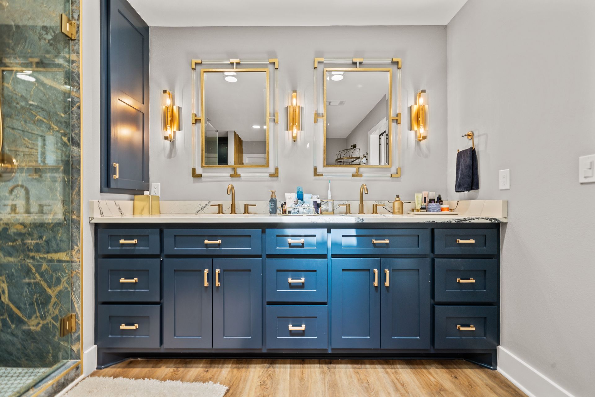 A bathroom with two sinks , two mirrors , and a walk in shower.