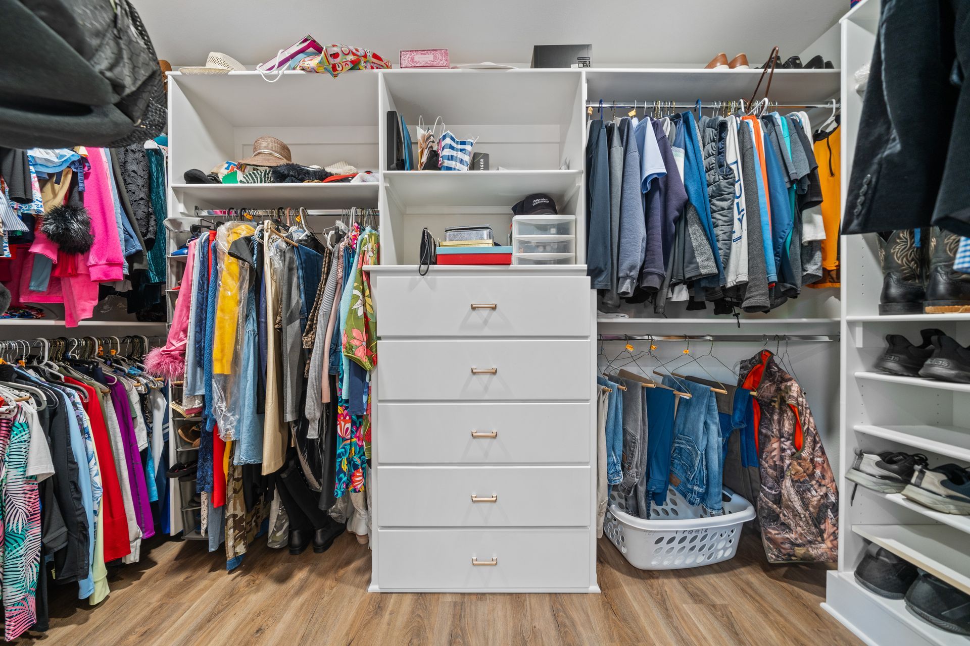 A walk in closet filled with lots of clothes and shoes.
