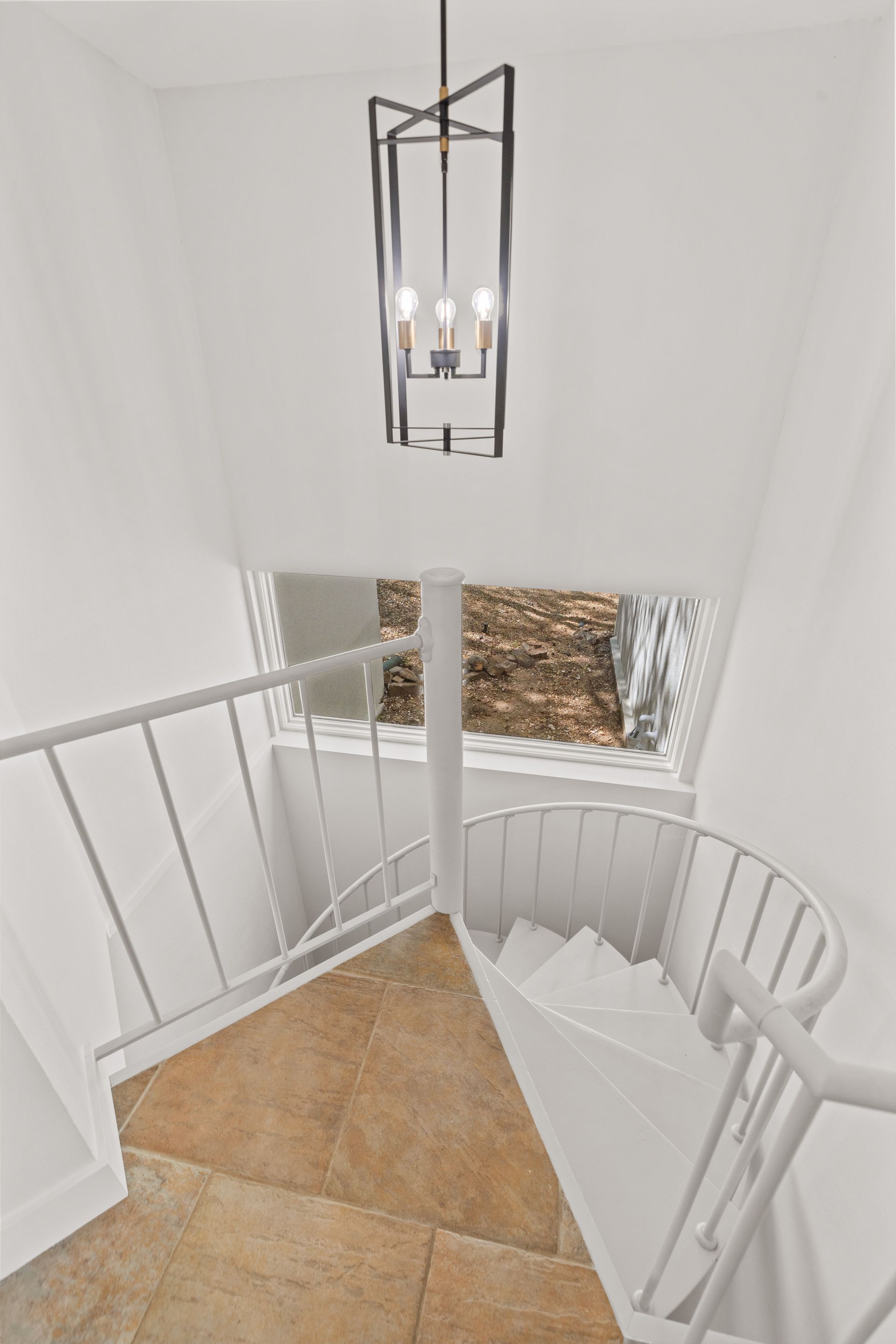 A spiral staircase with a chandelier hanging from the ceiling.