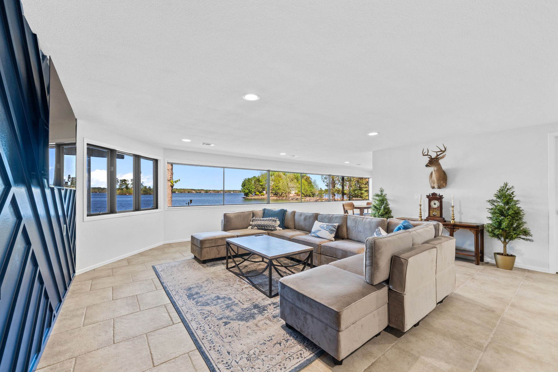 A living room with a large sectional couch and a clock on the wall.