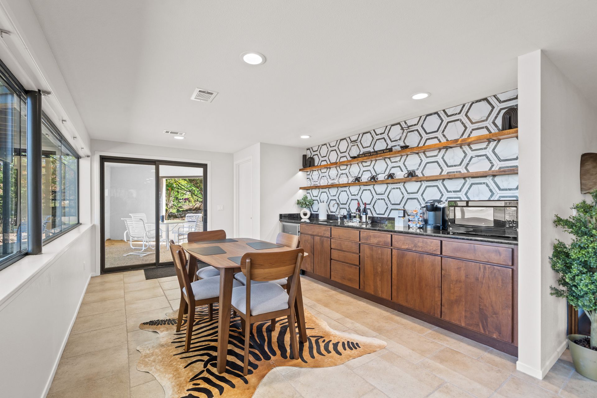 A dining room with a table and chairs and a cowhide rug.