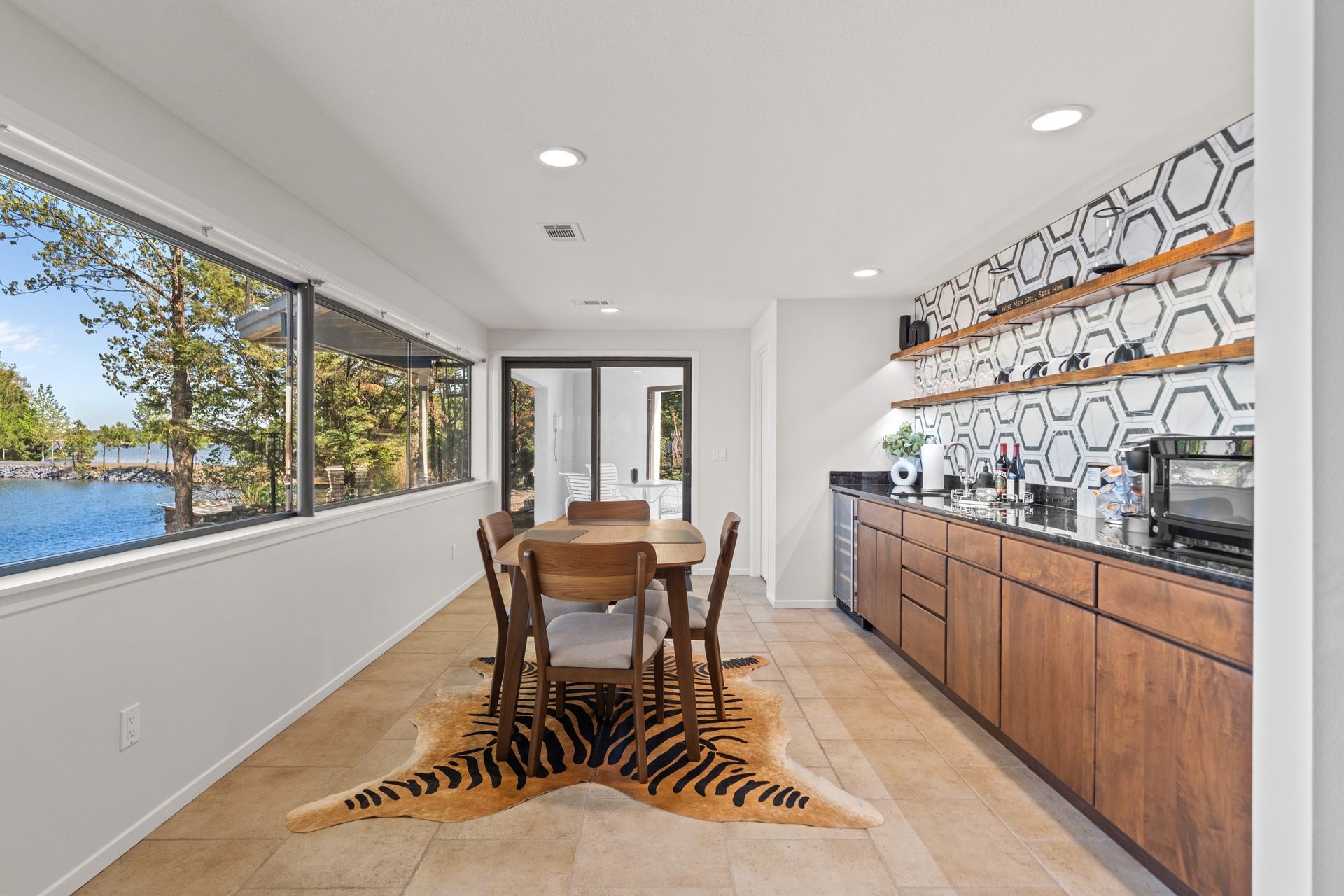 A dining room with a table and chairs and a cowhide rug.