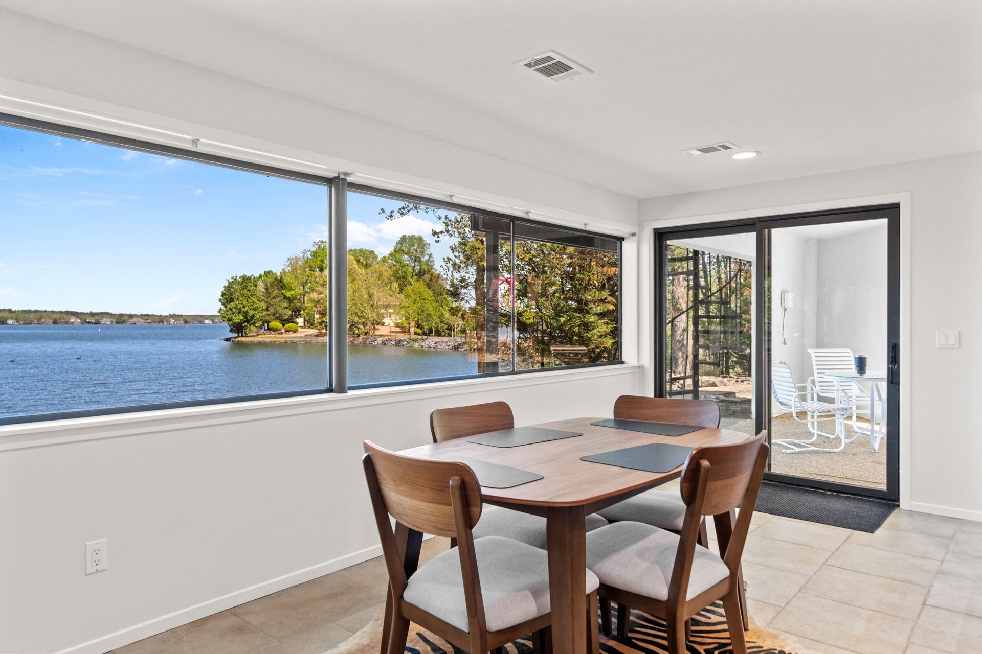 A dining room with a table and chairs and a view of a lake.