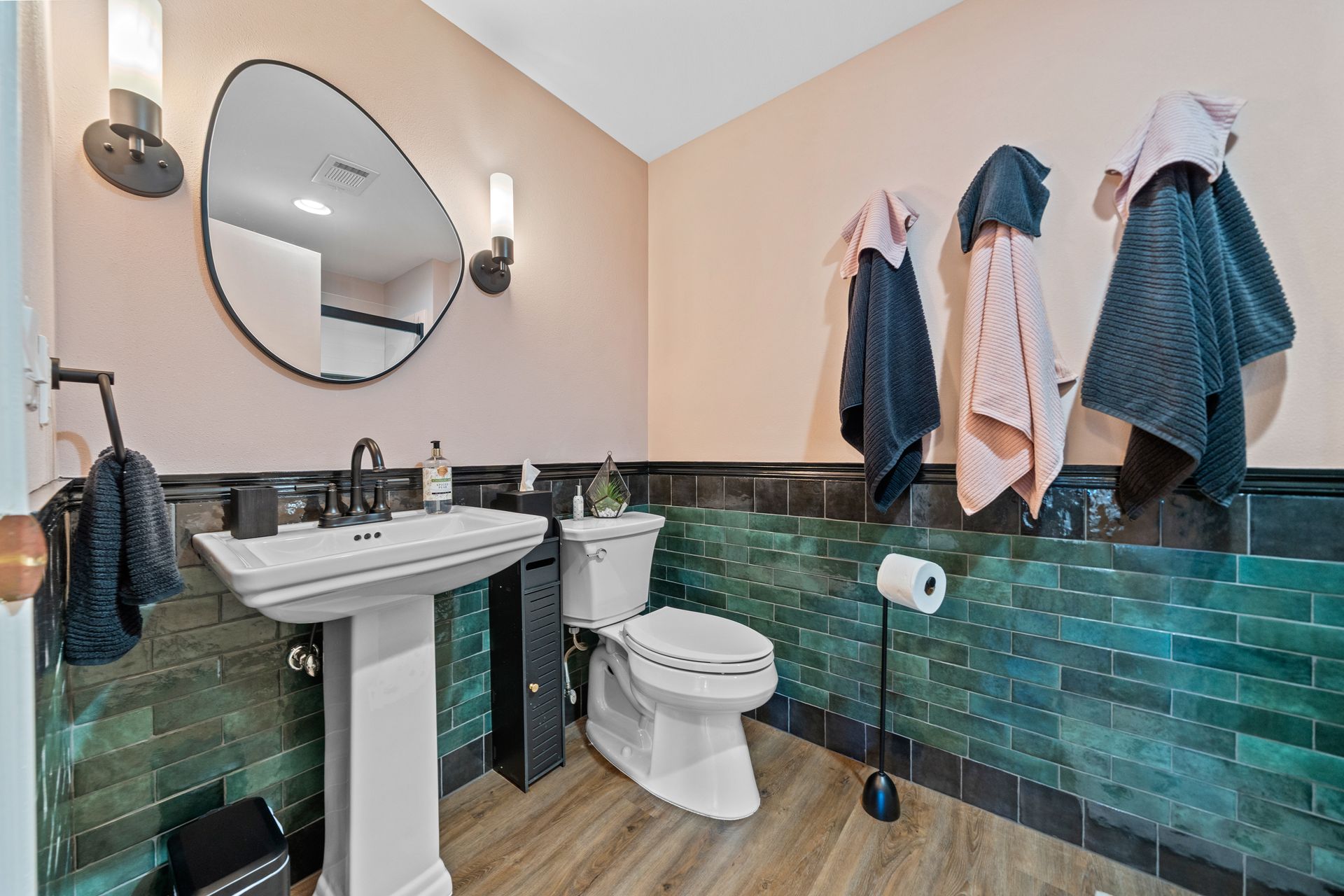 A bathroom with a toilet , sink , mirror and towels hanging on the wall.
