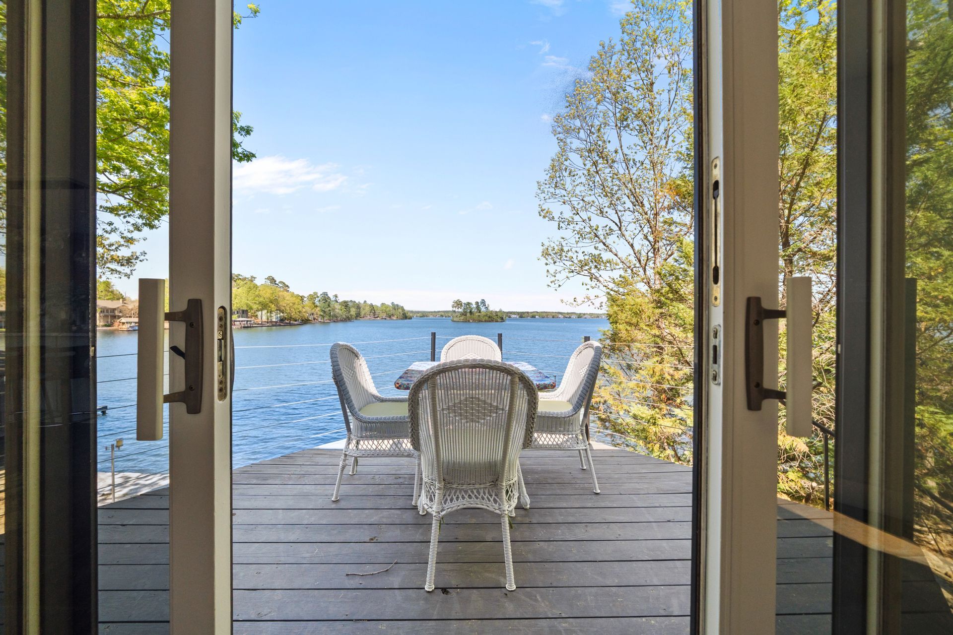 A patio with a table and chairs overlooking a lake.