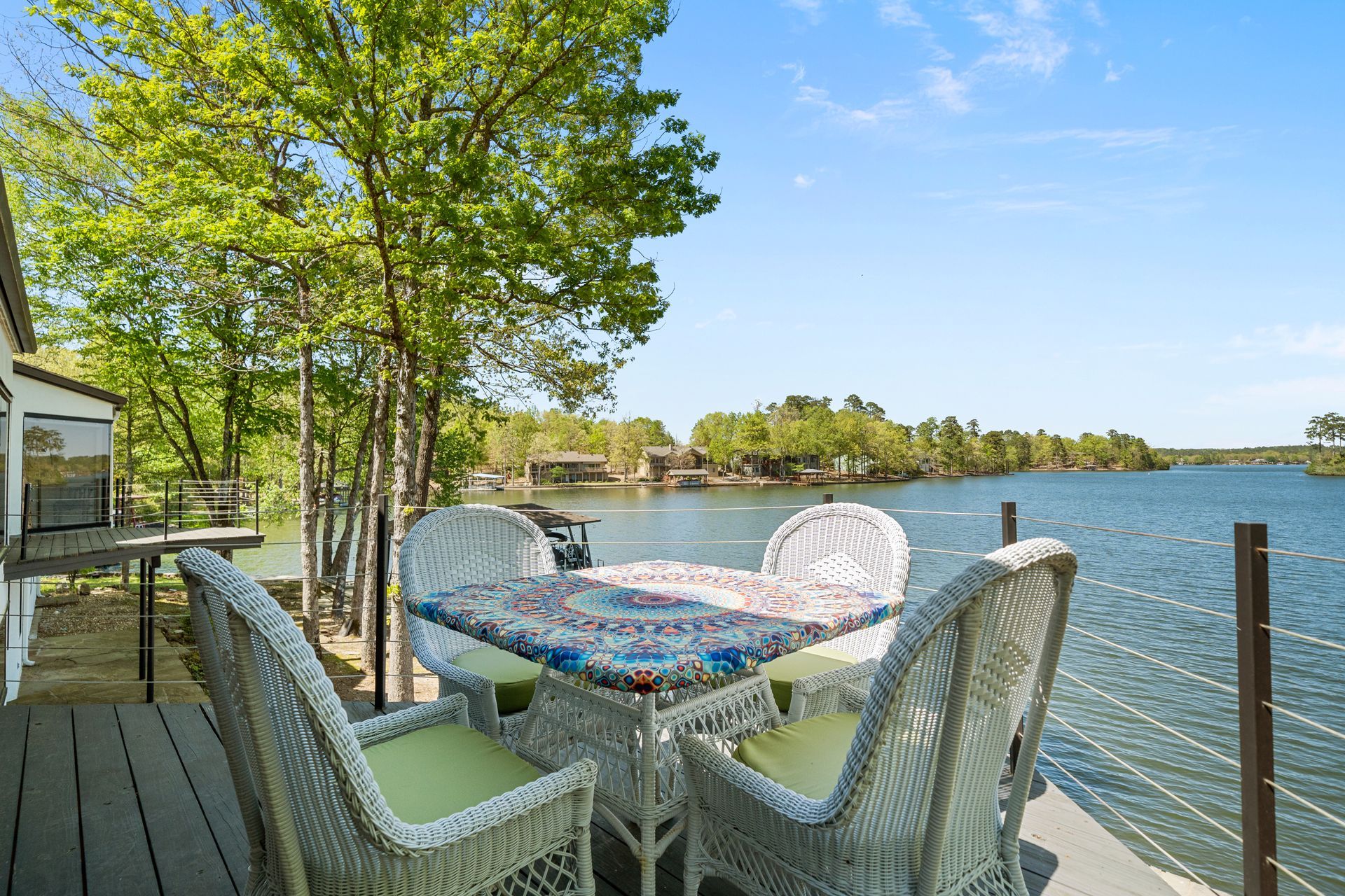 A table and chairs on a deck overlooking a lake.
