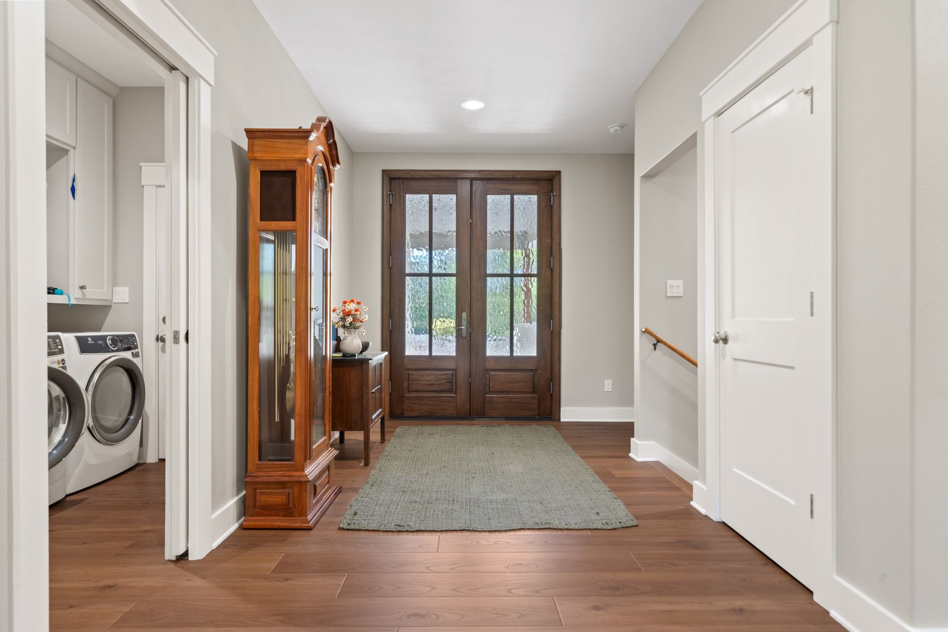 A hallway in a house with hardwood floors and a large grandfather clock.
