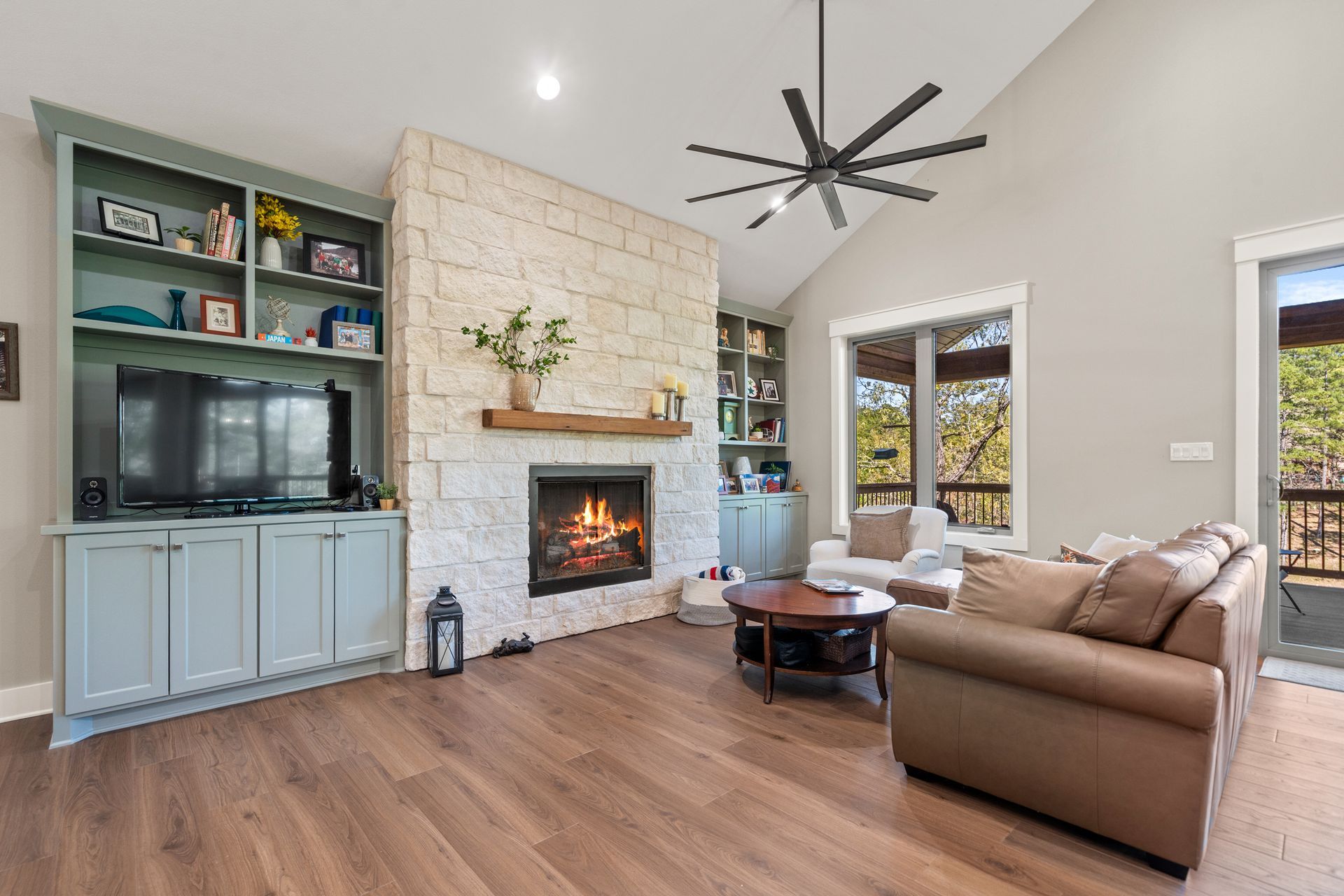 A living room with a fireplace and a ceiling fan.