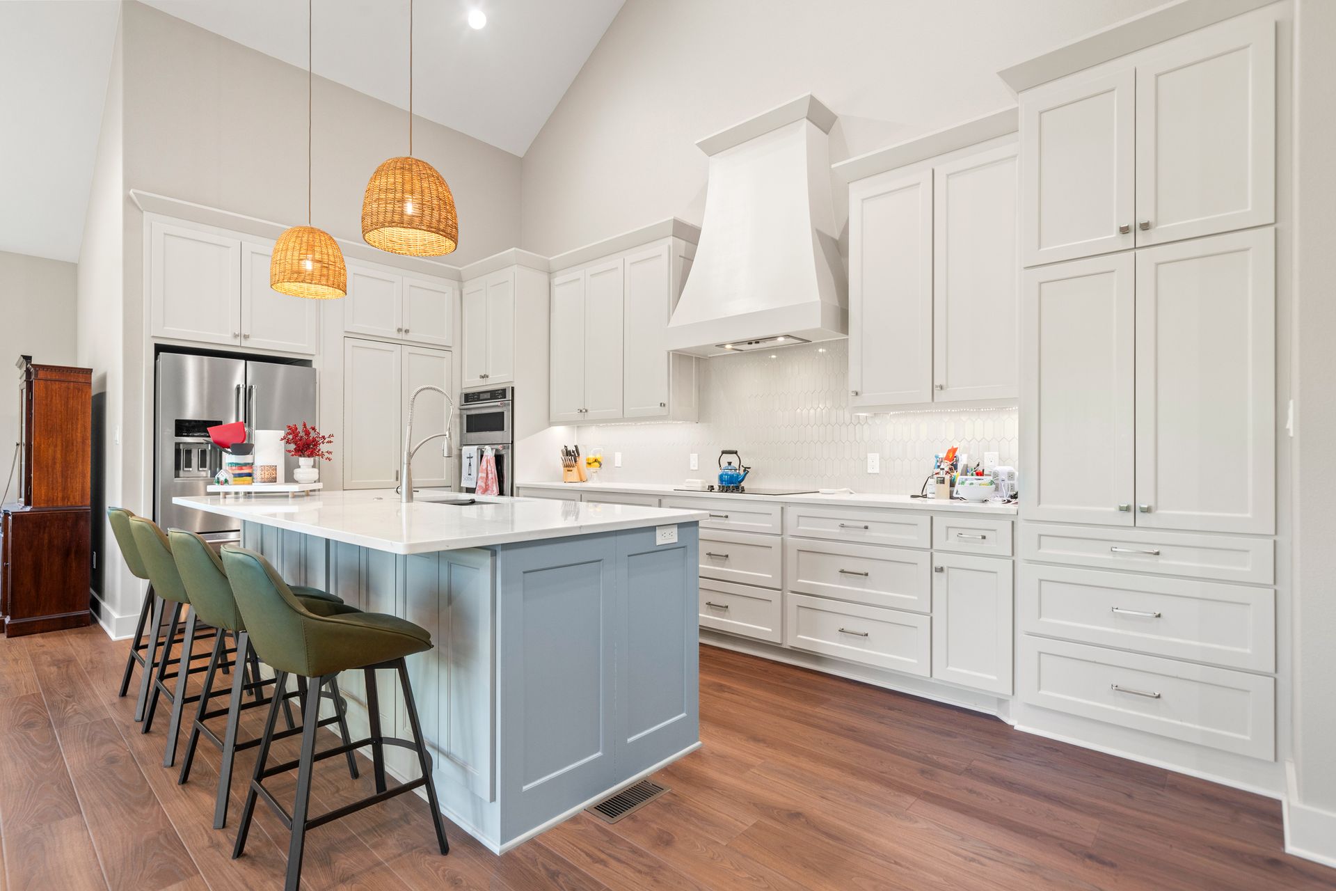 A kitchen with white cabinets , stainless steel appliances , and a large island.
