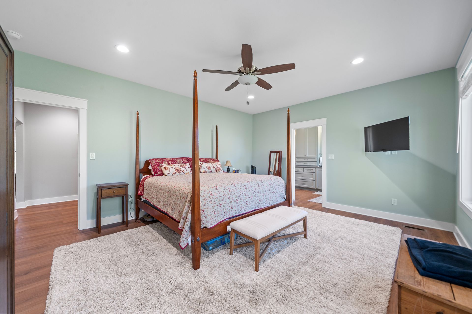 A bedroom with a four poster bed and a ceiling fan.