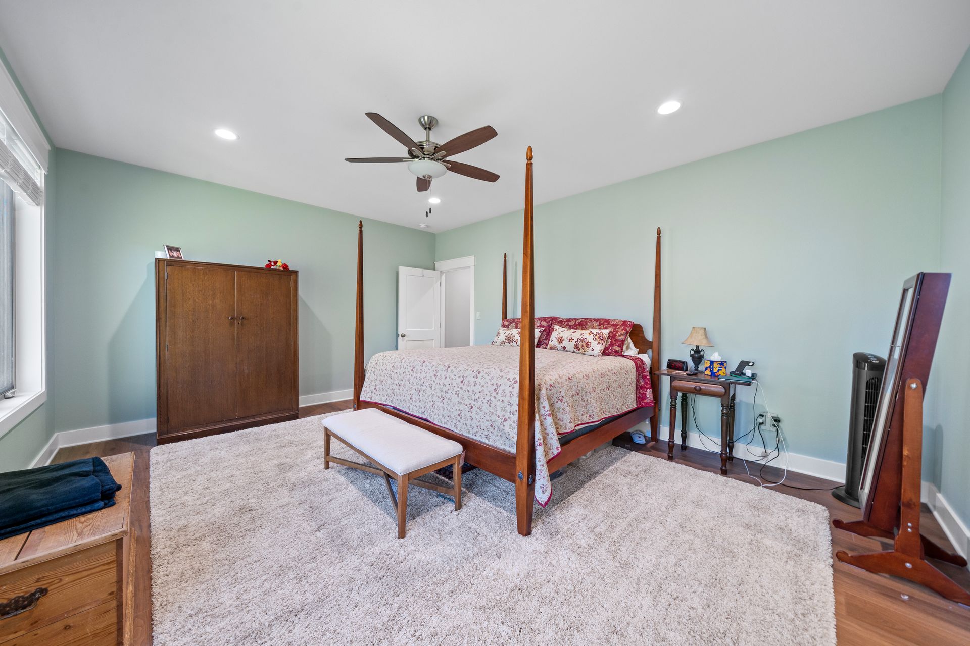 A bedroom with a four poster bed and a ceiling fan.