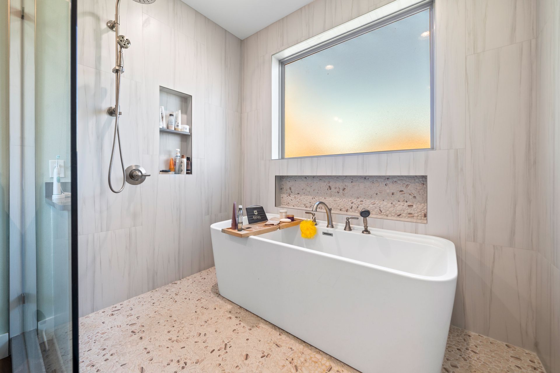 A bathroom with a bathtub , shower , and window.
