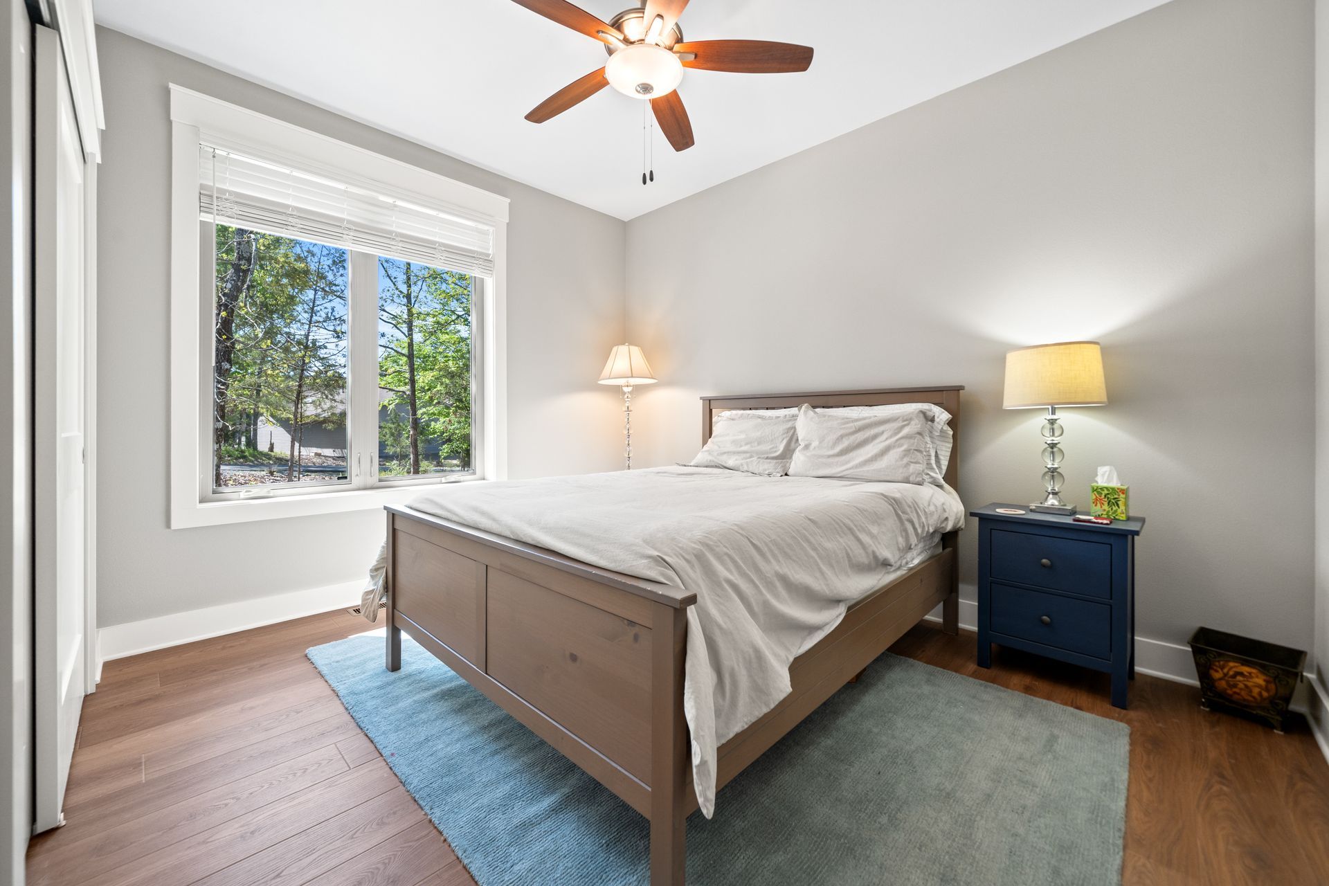 A bedroom with a bed , nightstand , lamp and ceiling fan.