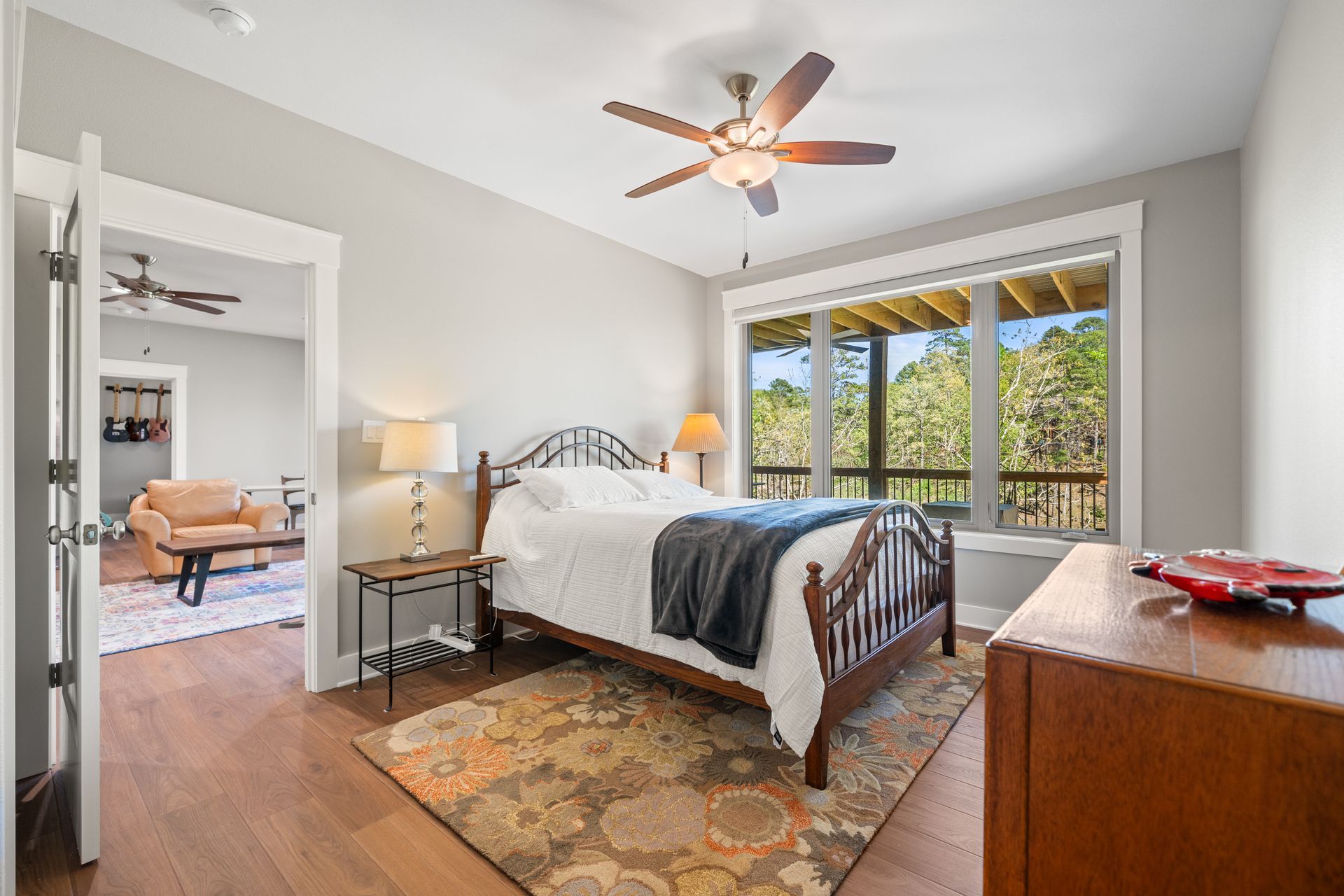 A bedroom with a bed , dresser , rug and ceiling fan.