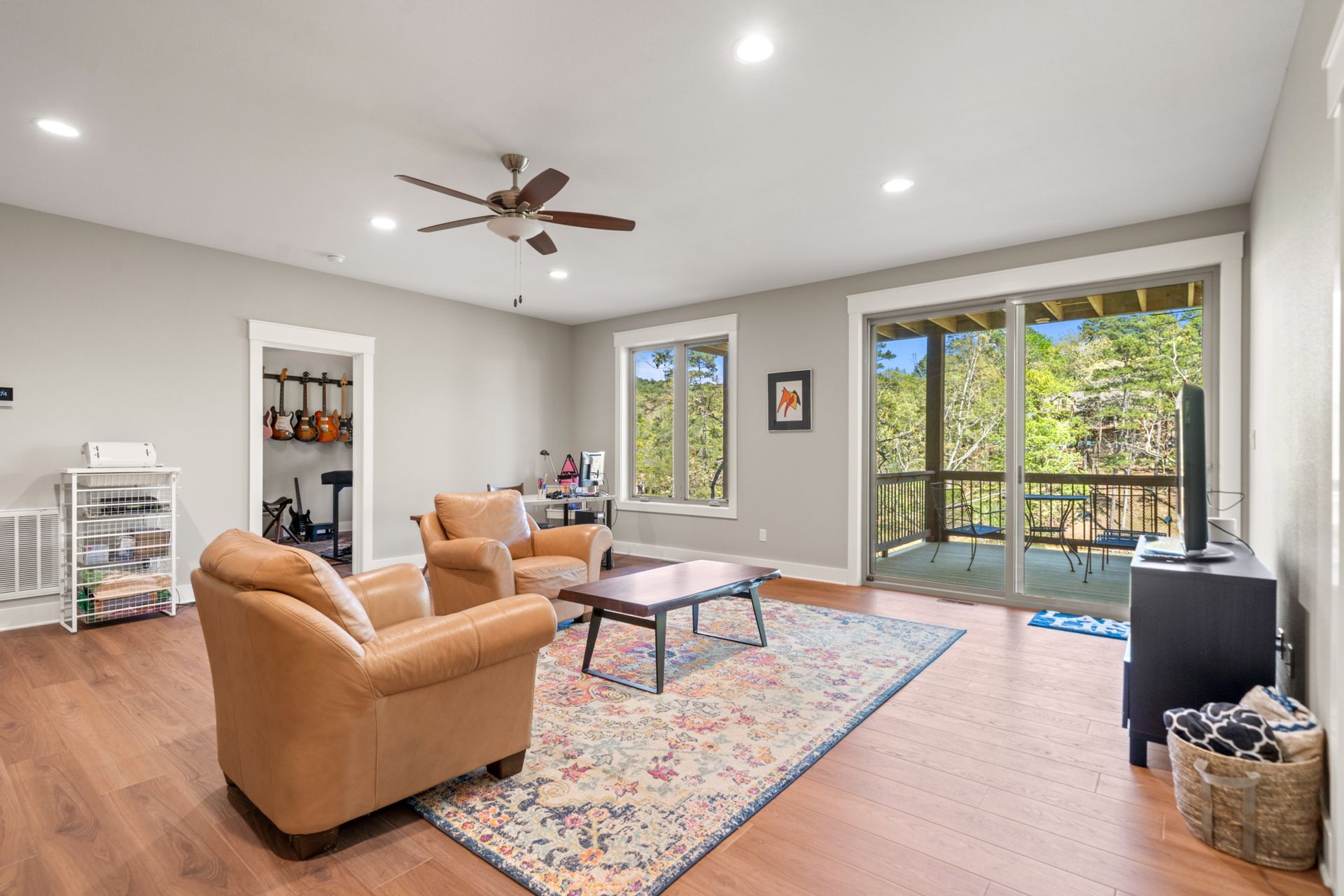 A living room with two chairs , a coffee table , and a ceiling fan.