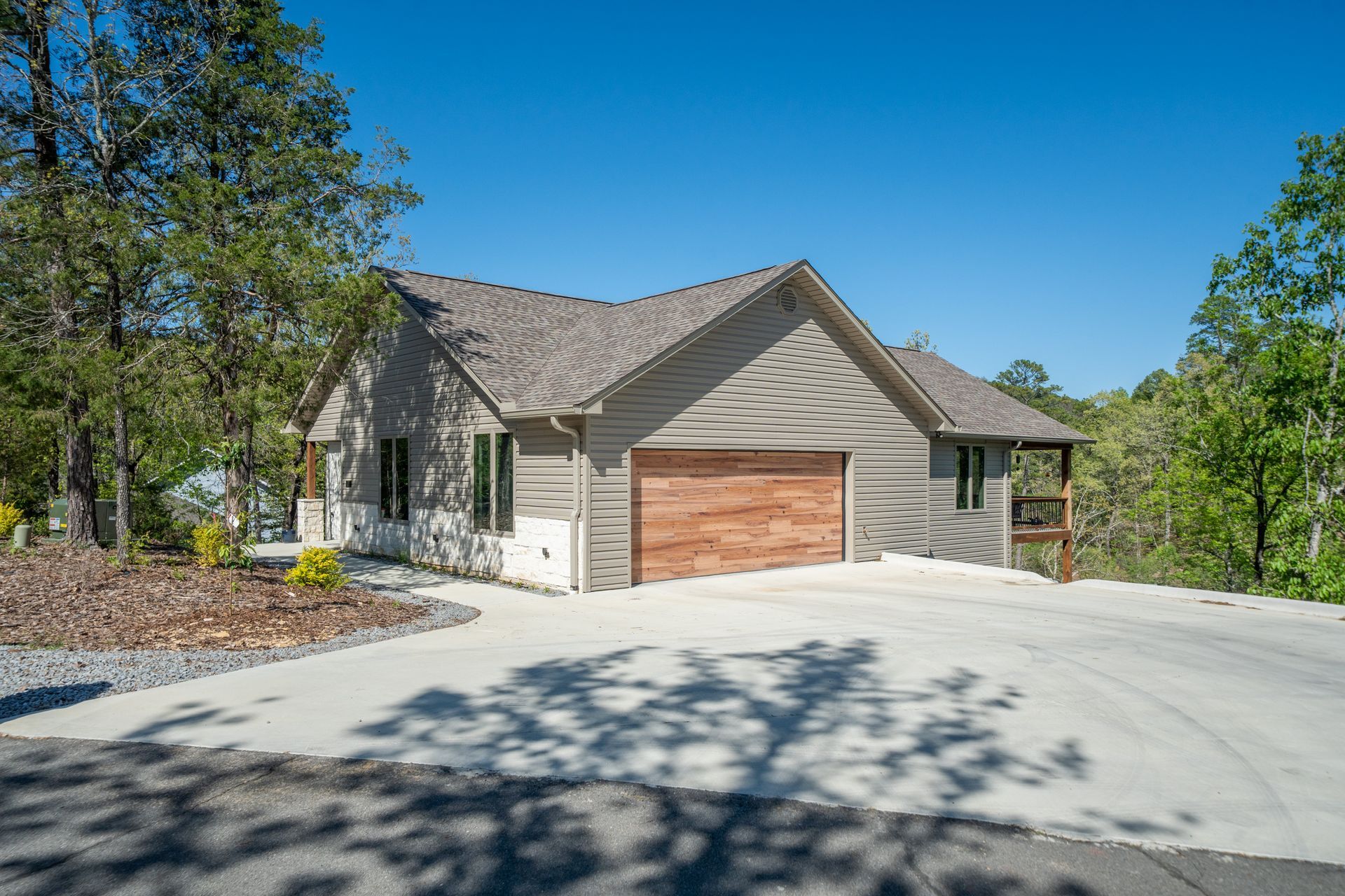 A house with a garage and a driveway is surrounded by trees.