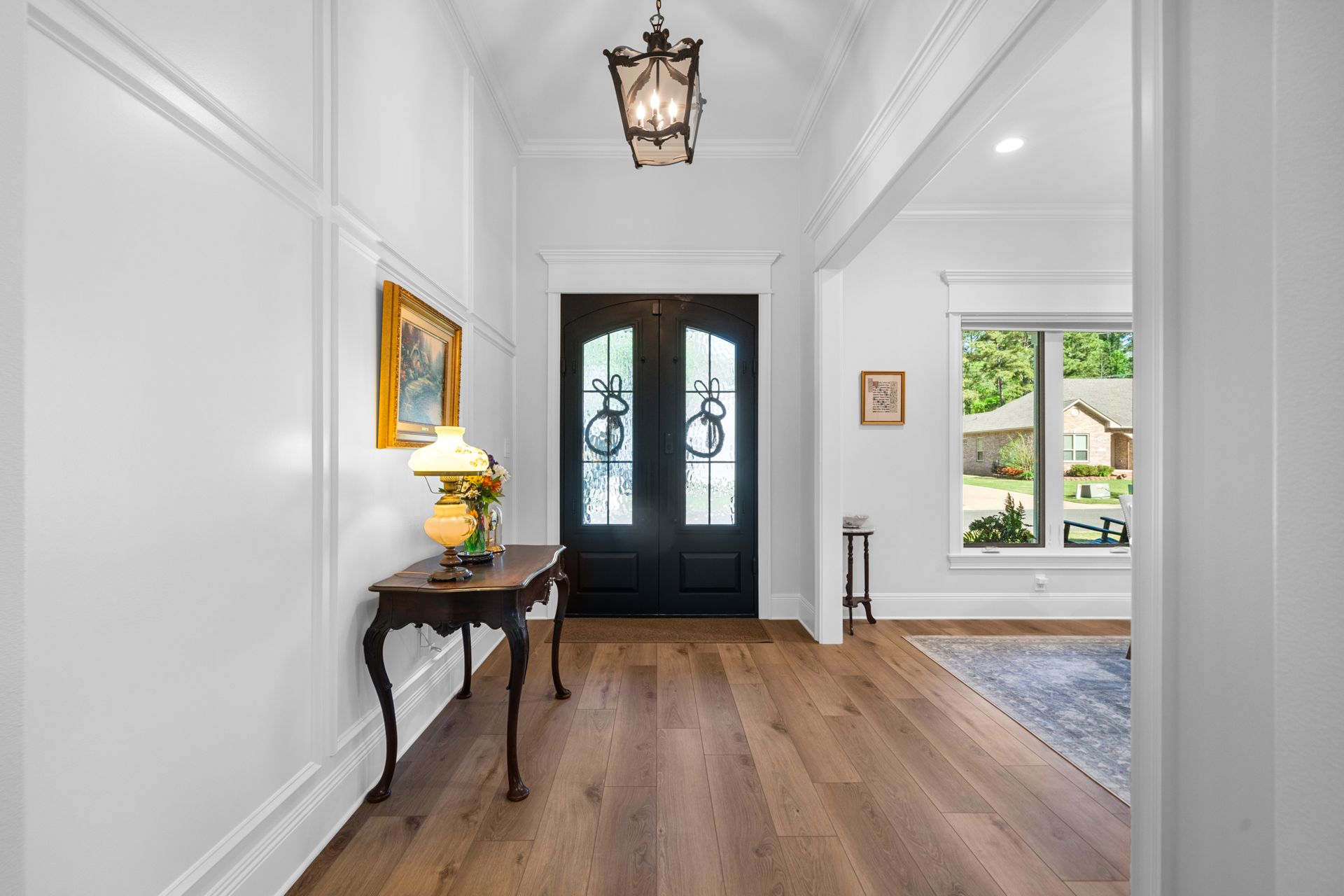 A hallway in a house with hardwood floors and a black door.