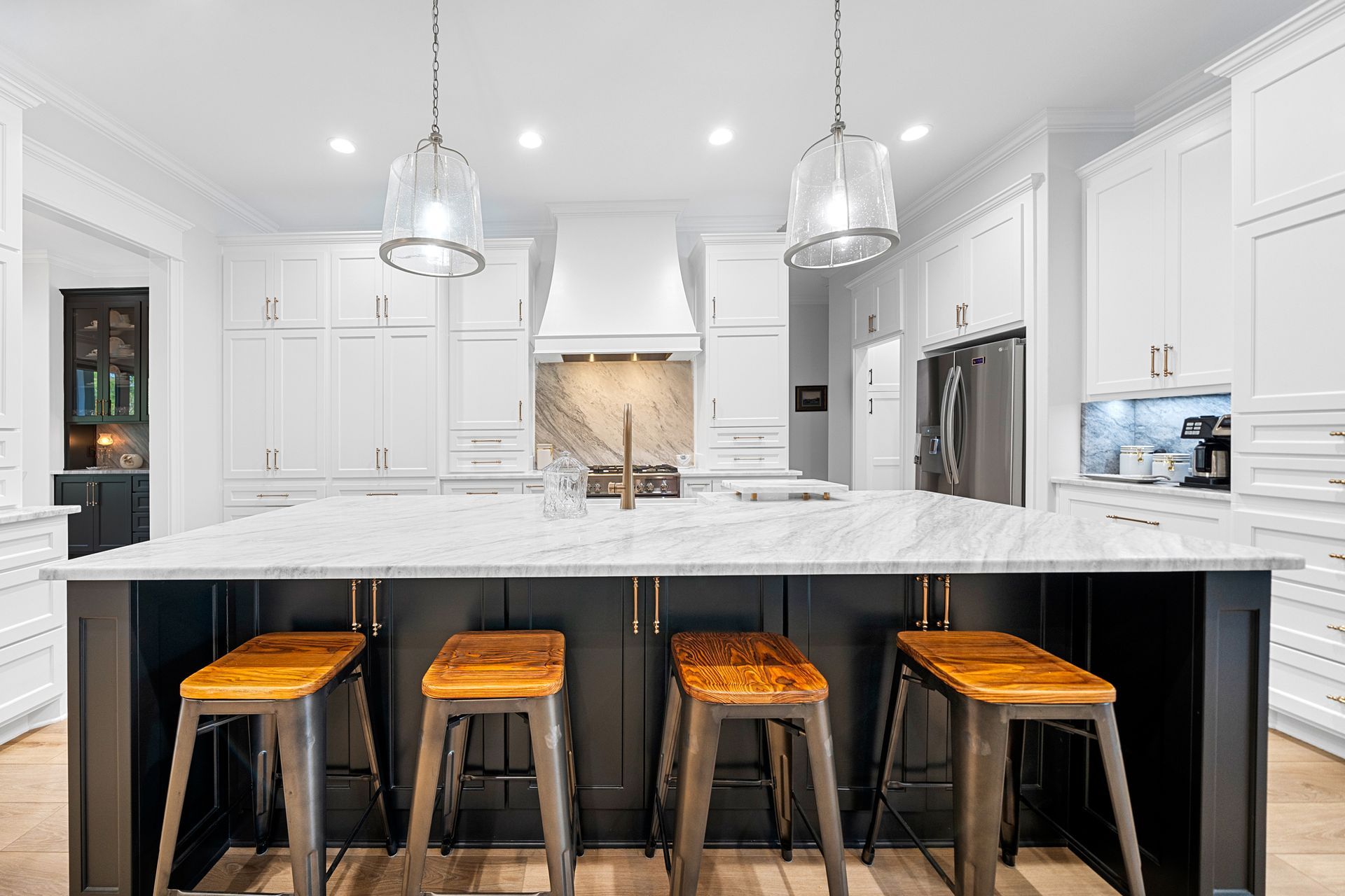 A kitchen with a large island and stools in it.