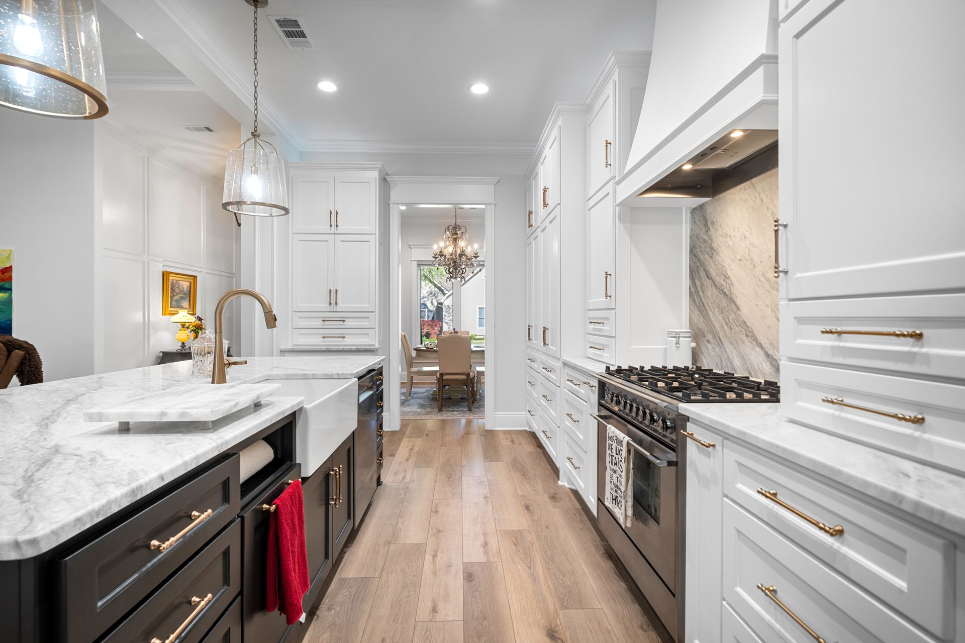A kitchen with white cabinets , stainless steel appliances , hardwood floors and a sink.