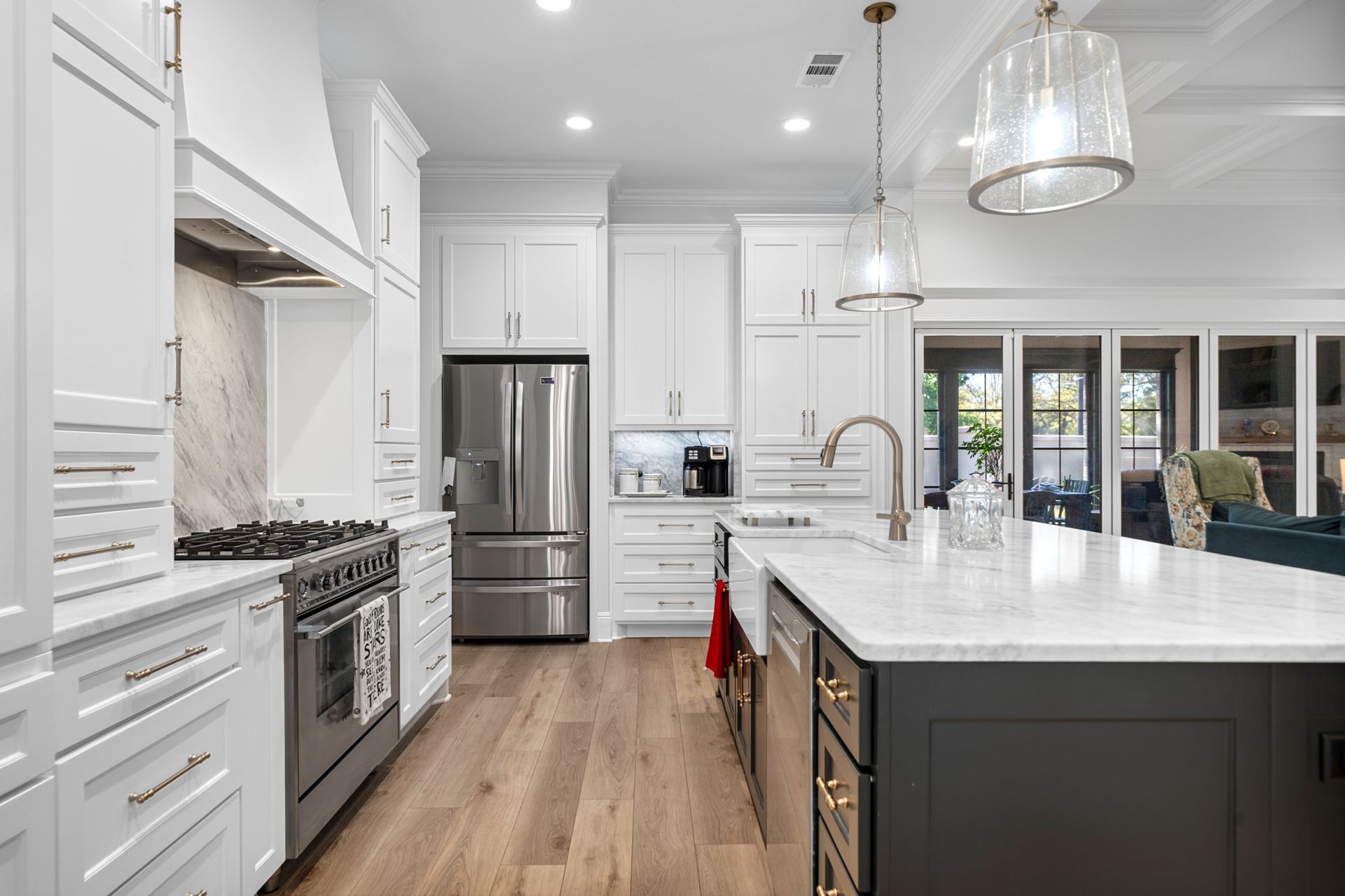 A kitchen with white cabinets , stainless steel appliances , and a large island.