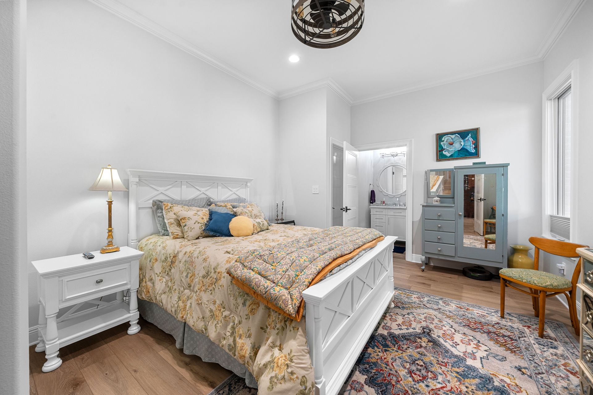 A bedroom with a bed , nightstand , chair and rug.