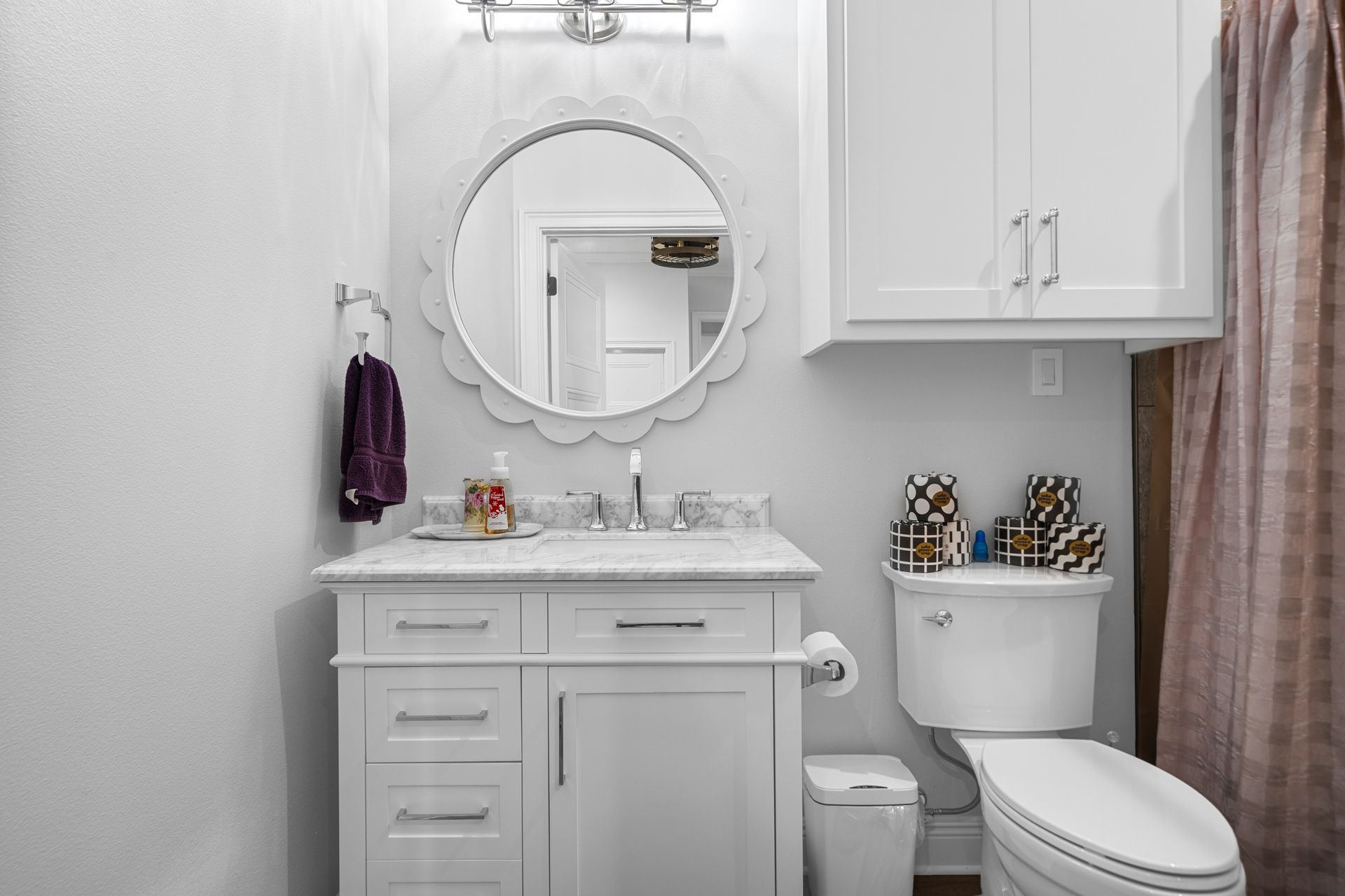 A bathroom with a sink , toilet , mirror and shower curtain.